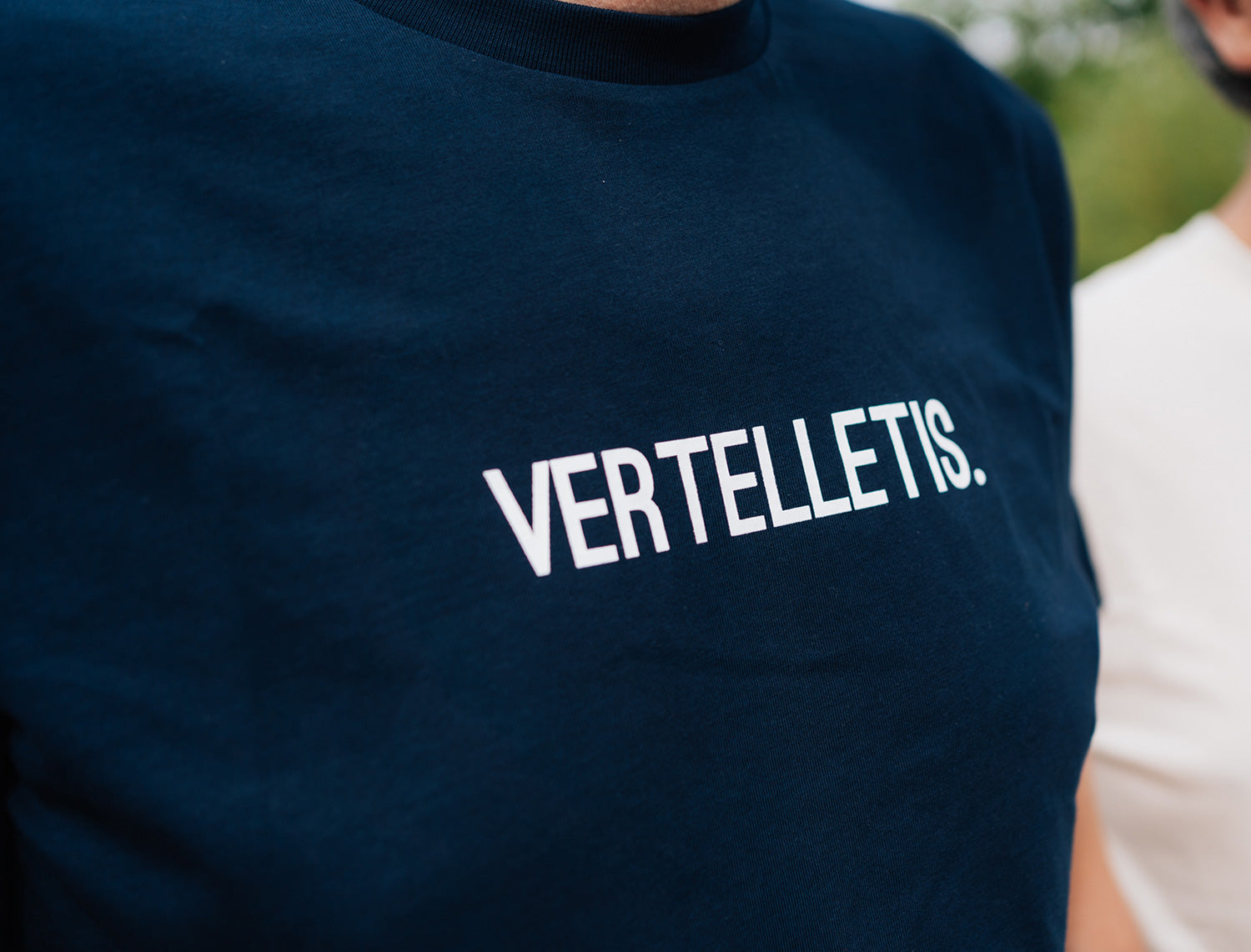 Close-up van een donkerblauwe T-shirt met opdruk VERTELLETIS.