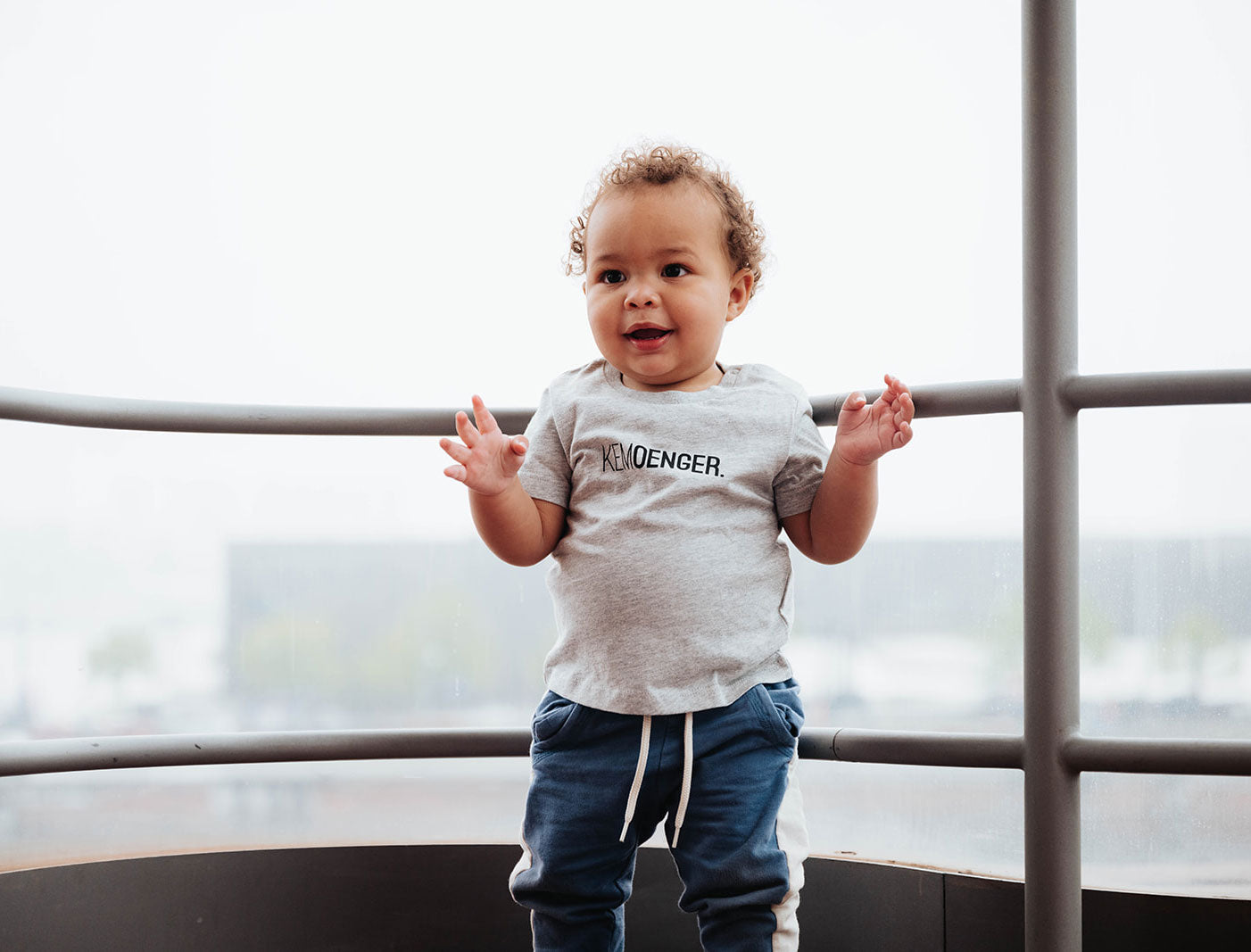 Baby met een grijze T-shirt voor baby's met opdruk KEMOENGER.