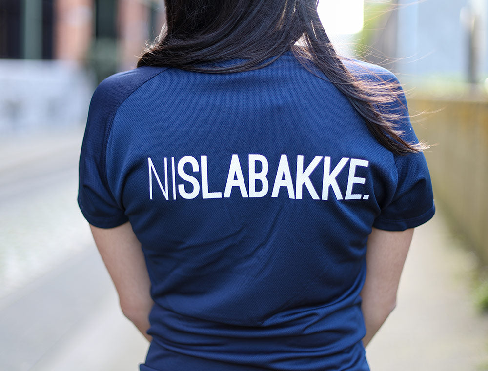 Close-up van een blauwe loopshirt met opdruk NISLABAKKE.