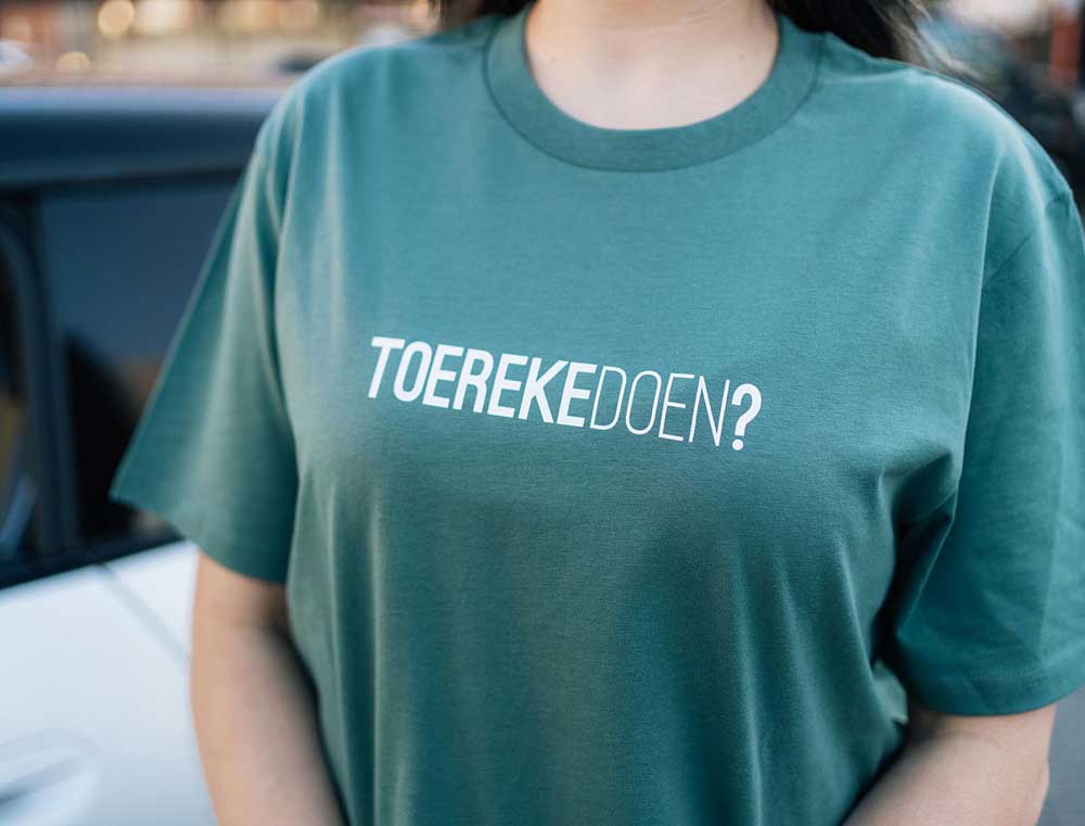 Close-up van een groene T-shirt met opdruk TOEREKEDOEN?
