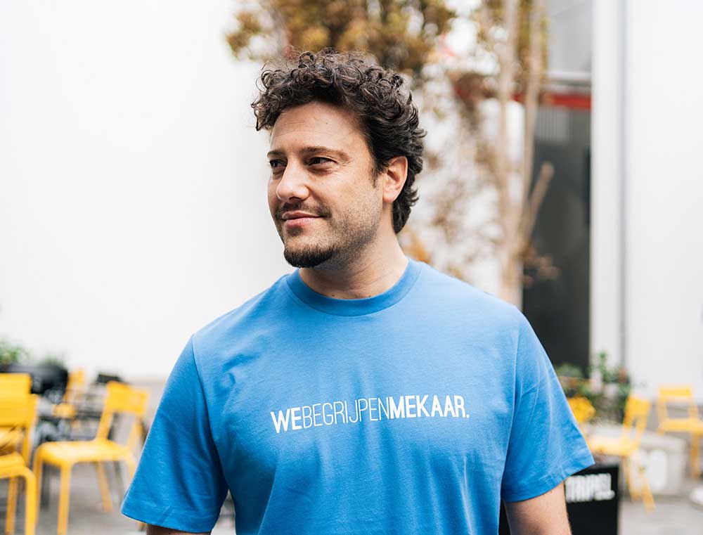 Man met een blauwe T-shirt met opdruk WEBEGRIJPENMEKAAR.