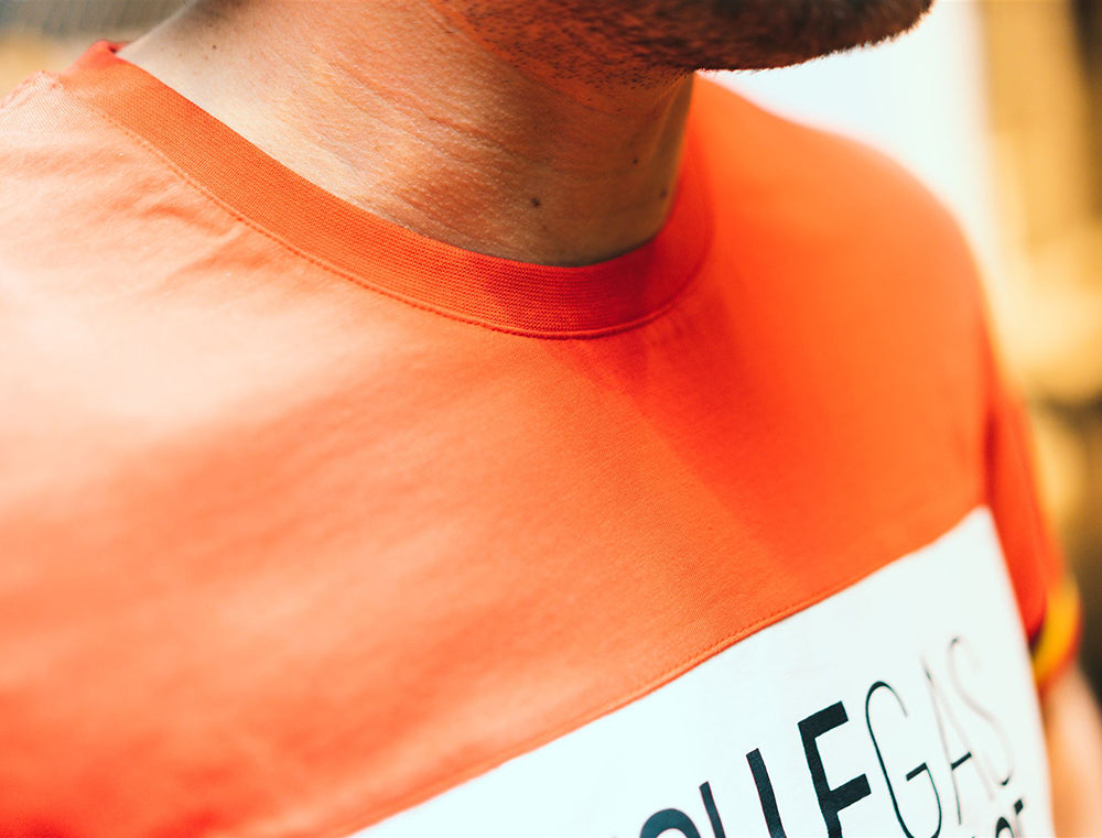Close-up van pasvorm aan de nek van rode T-shirt met opdruk VOLLEGASGENESURPLACE.