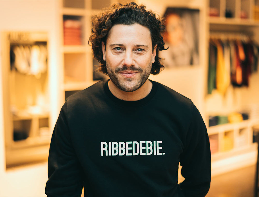 Man met zwarte sweater met opdruk RIBBEDEBIE.