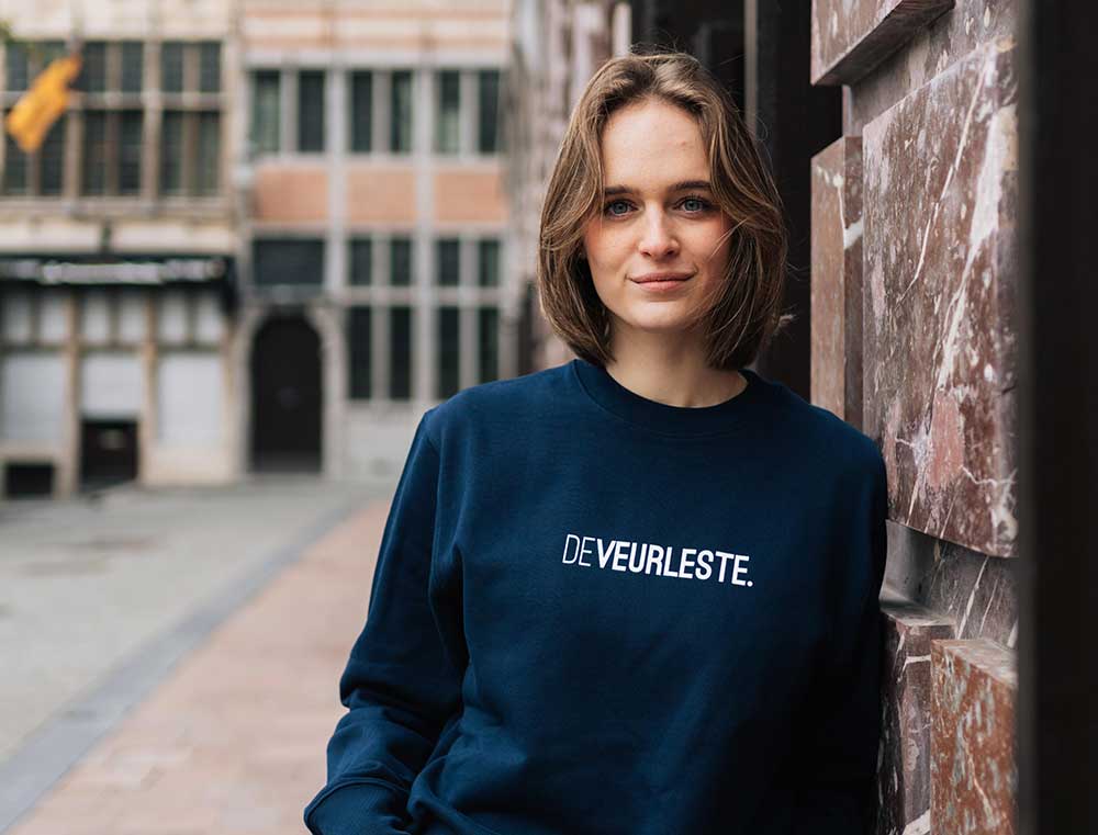 Vrouw met donkerblauwe sweater met opdruk DEVEURLESTE.