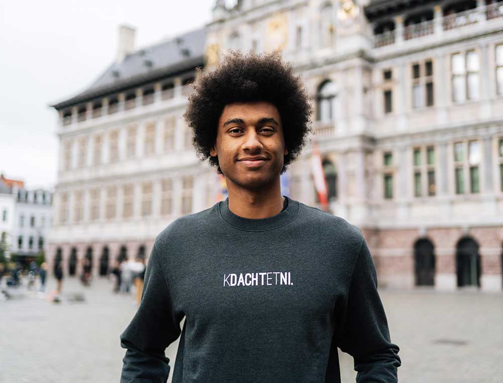 Man met een donkergrijze sweater met opdruk KDACHTETNI.