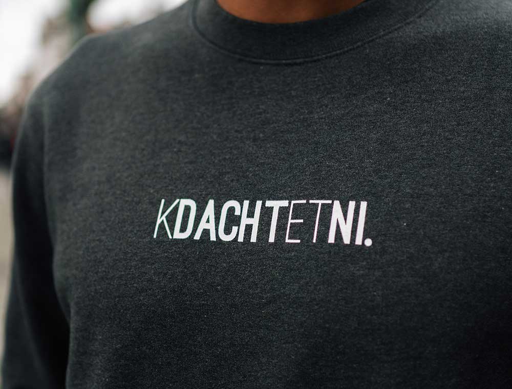 Close-up van grijze sweater met opdruk KDACHTETNI.