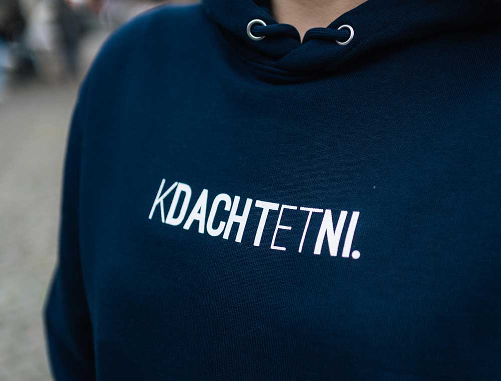 Vrouw met een donkerblauwe hoodie met opdruk KDACHTETNI.