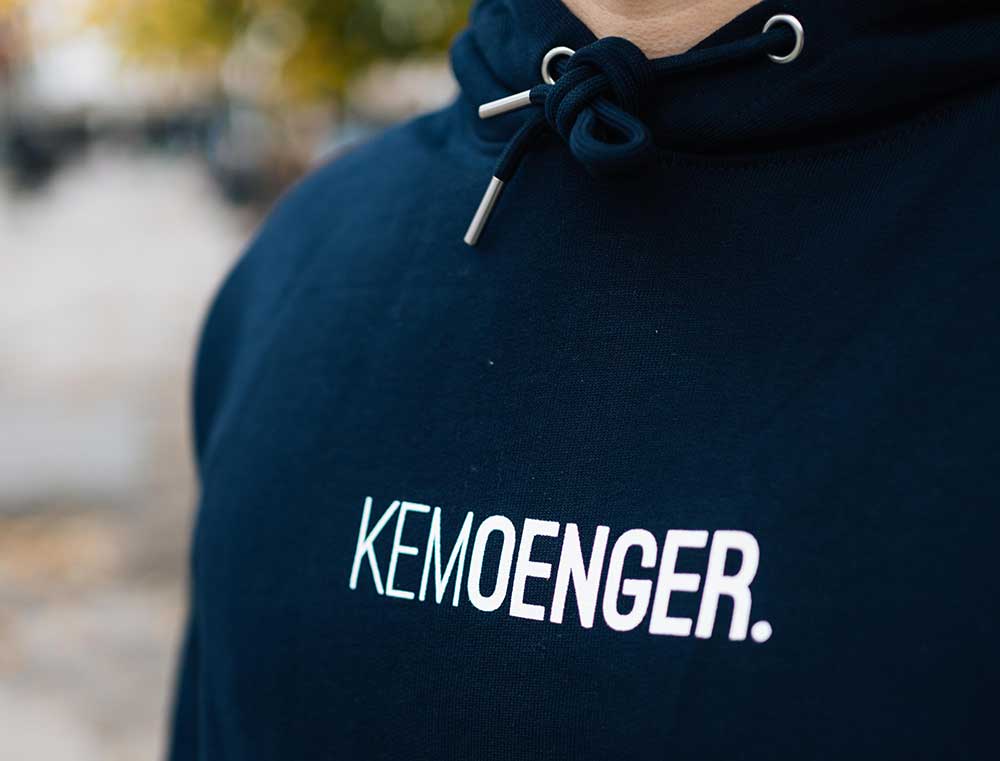 Man met een donkerblauwe hoodie met opdruk KEMOENGER.