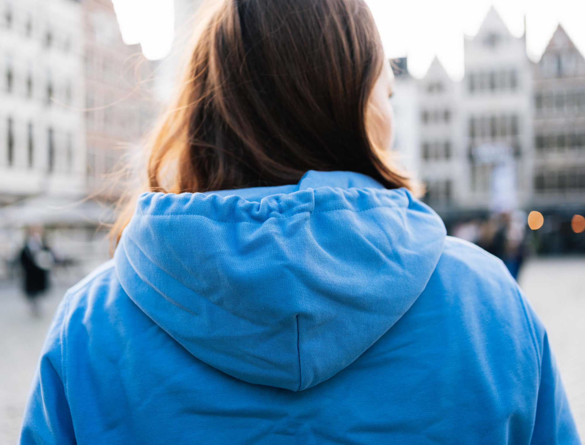 Achterkant van vrouw met blauwe hoodie met opdruk JUFFRATOERTJES.