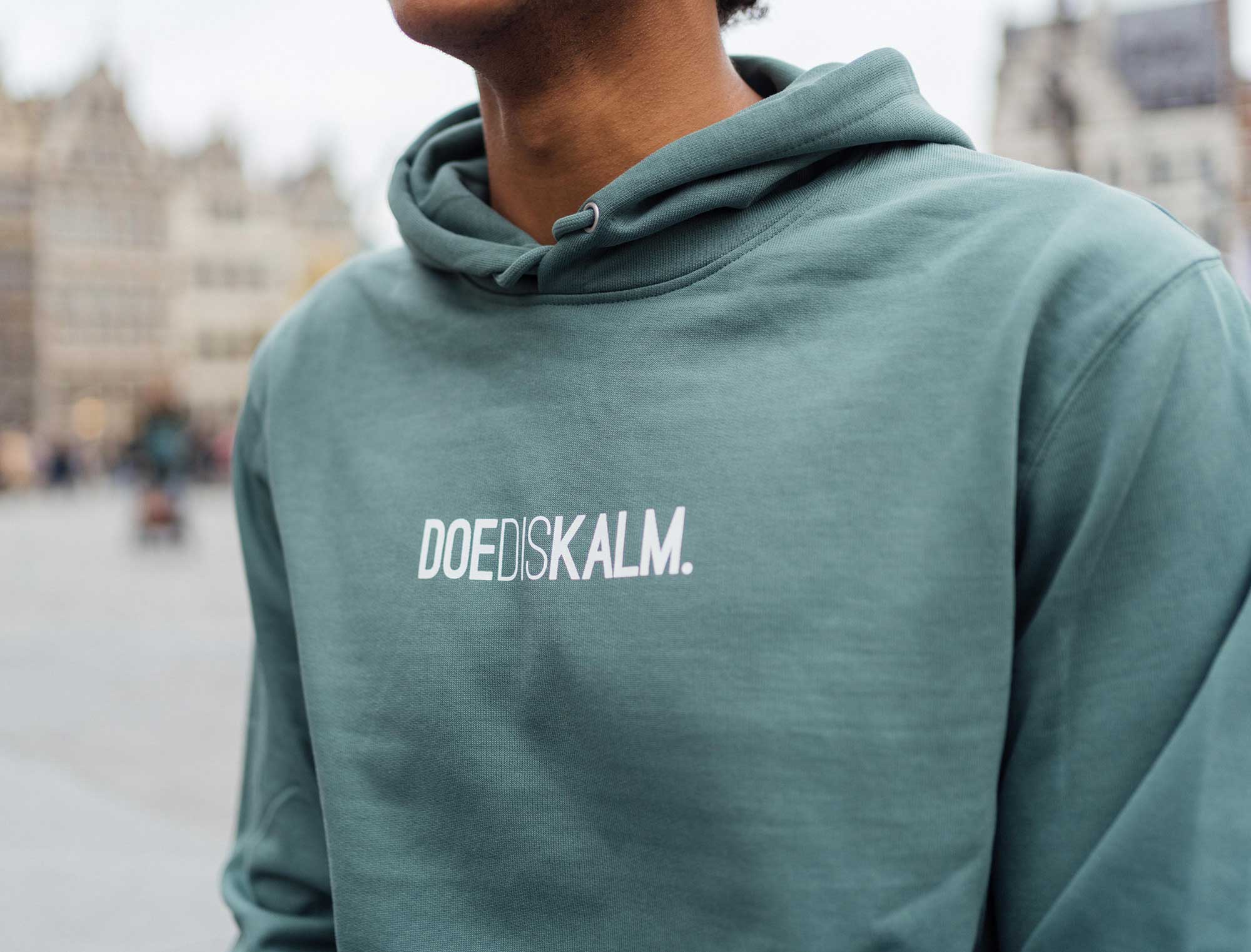 Close-up van groene hoodie met opdruk DOEDISKALM.