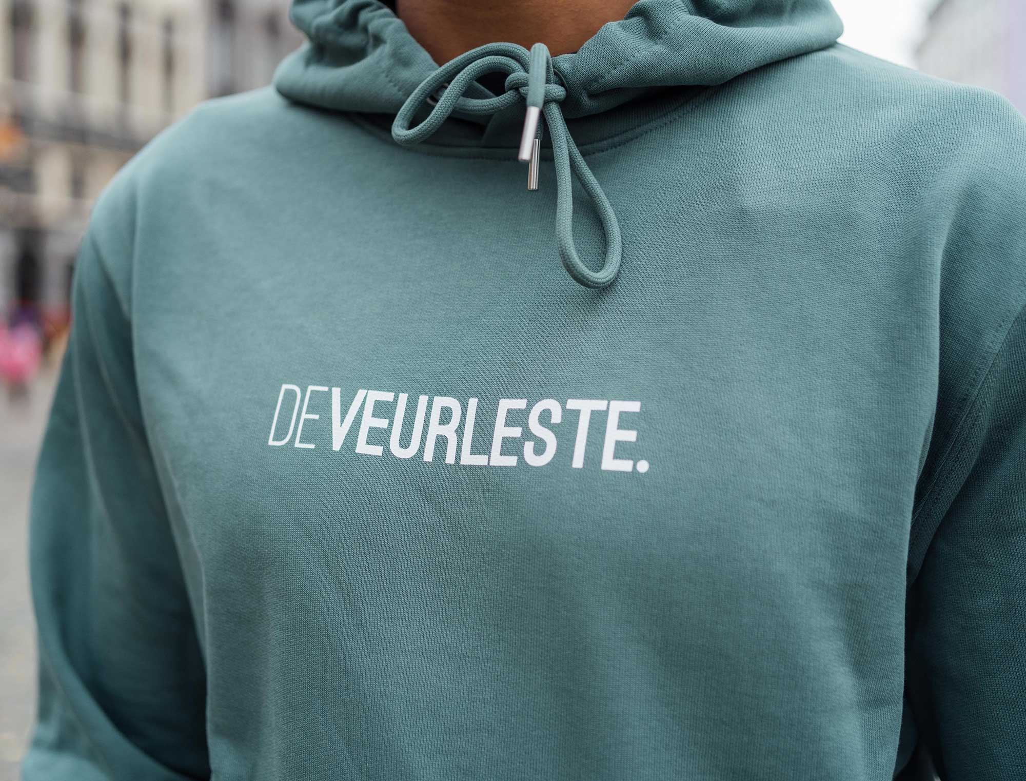 Man met groene hoodie met opdruk DEVEURLESTE.