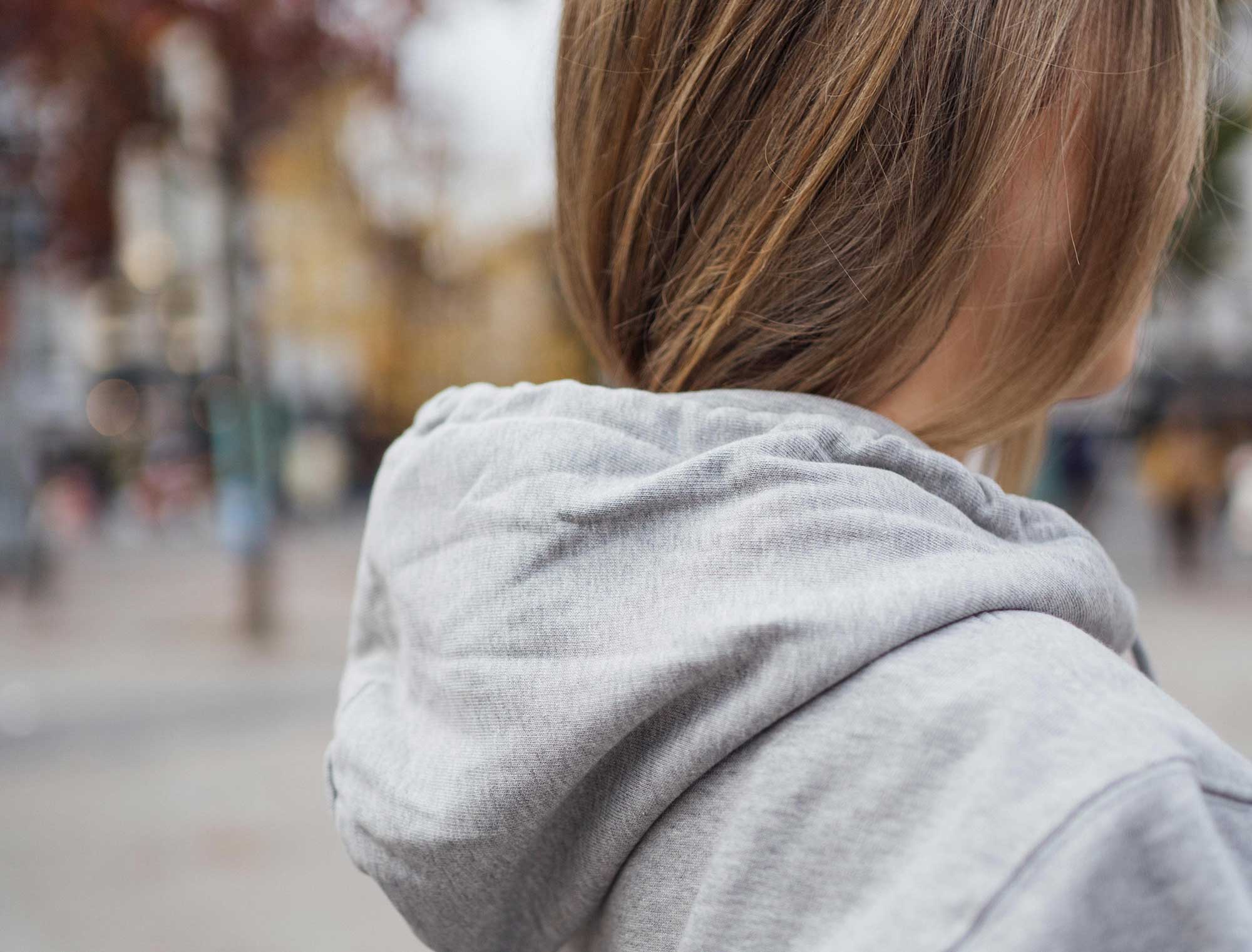 Vrouw met grijze hoodie met opdruk ALEGAST.