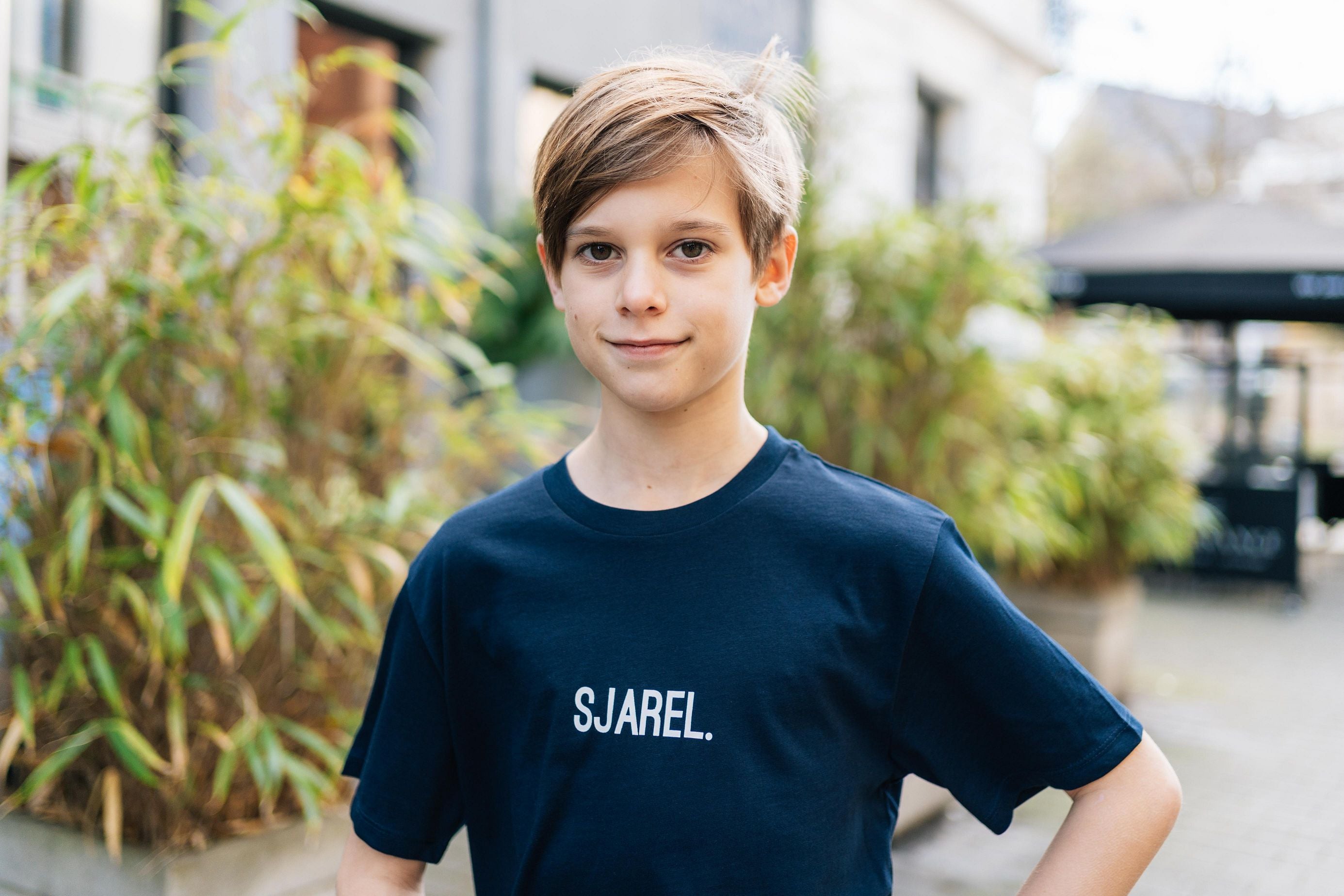 Jongen met een donkerblauwe T-shirt met opdruk SJAREL. voor kinderen