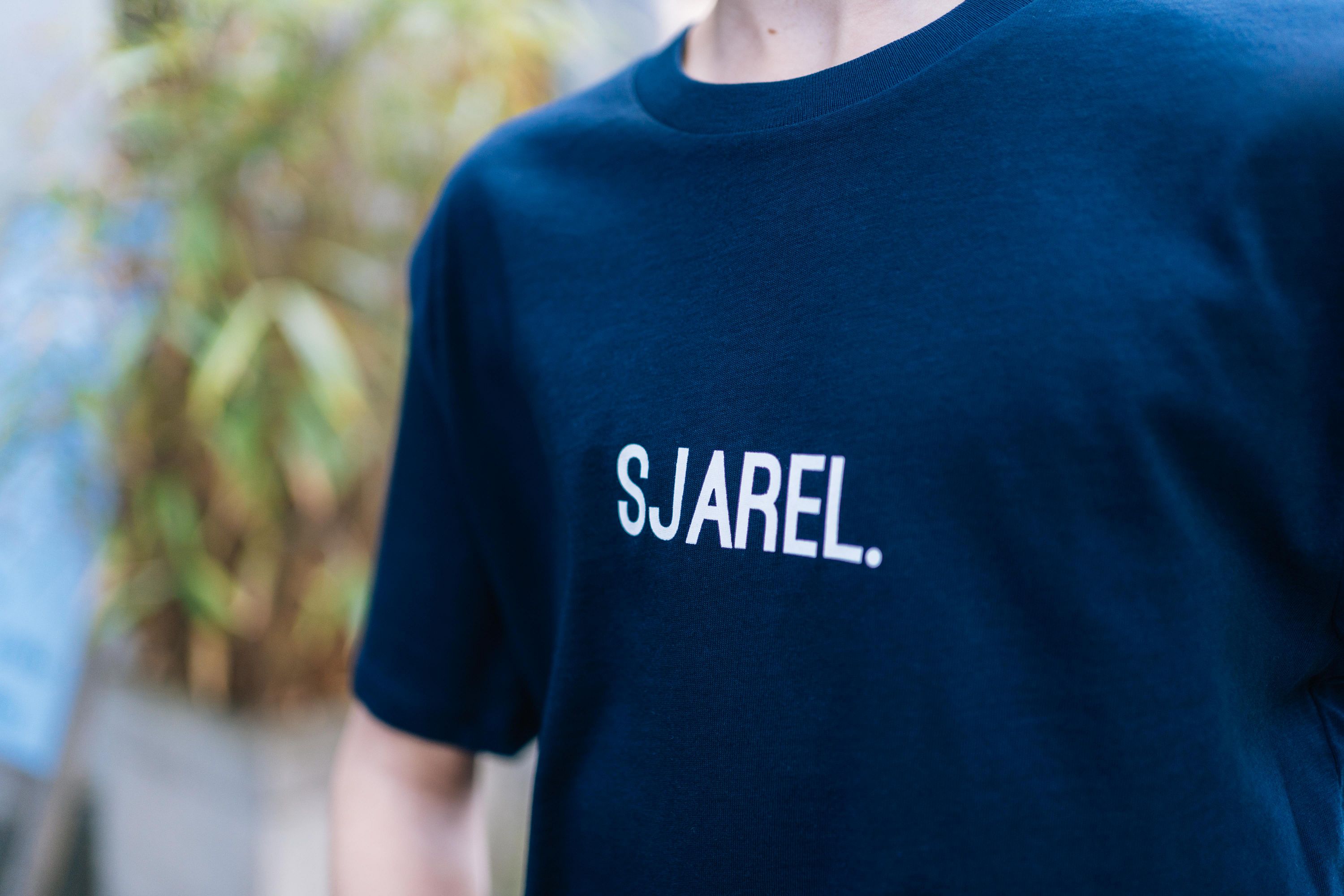 Close-up van een donkerblauwe T-shirt met opdruk SJAREL. voor kinderen