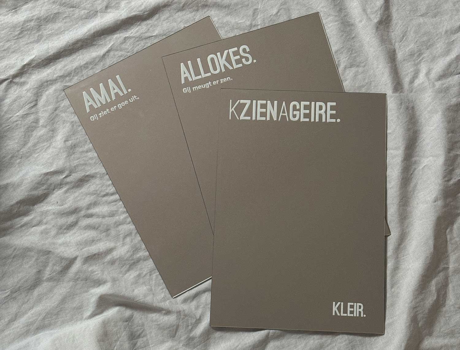 Vooraanzicht van een spiegel met opdruk KZIENAGEIRE. Vooraanzicht van een spiegel met opdruk ALLOKES. Vooranzicht van spiegel met opdruk AMAI. Drie verschillende spiegels met opdruk.