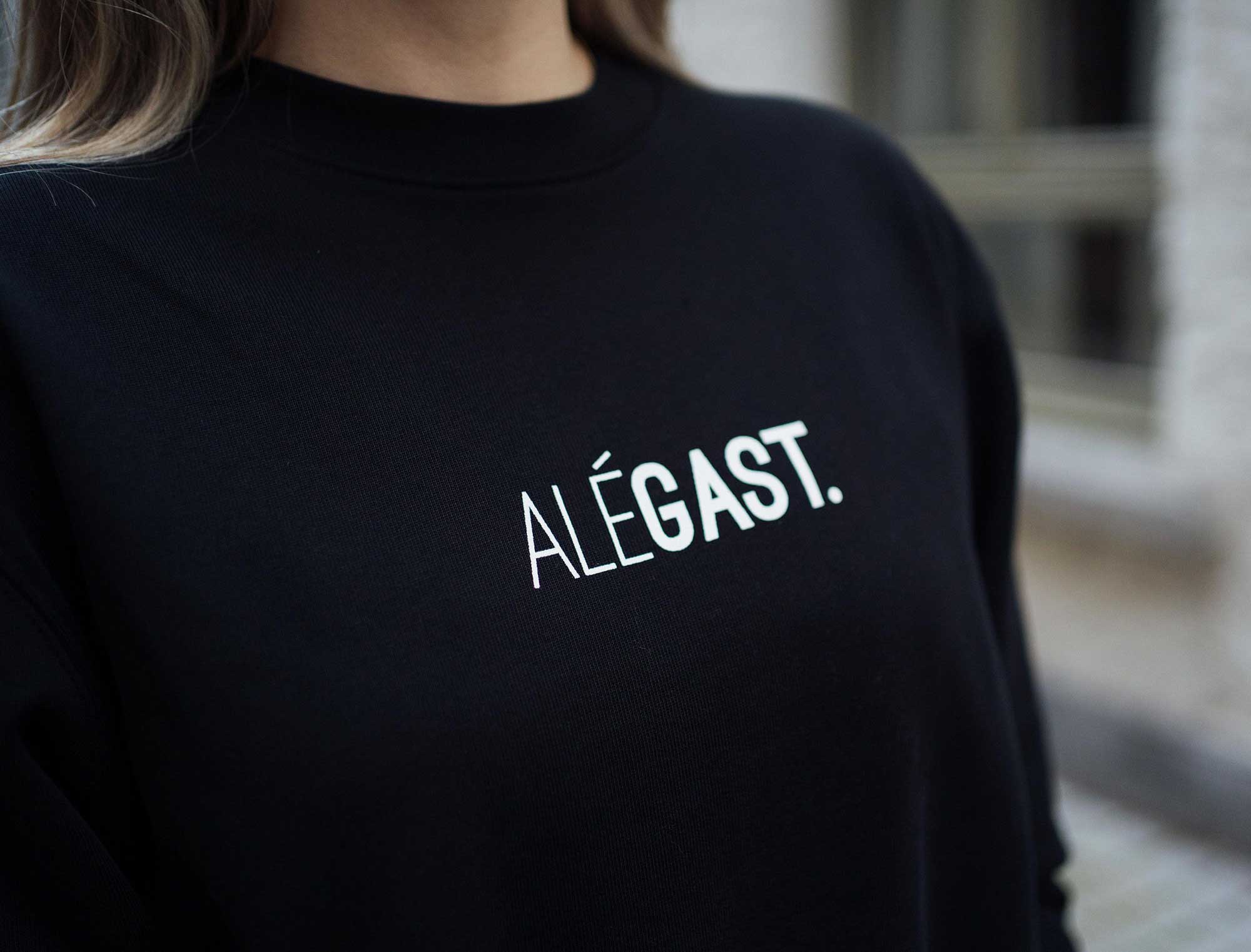 Close-up van een zwarte sweater met opdruk ALEGAST.