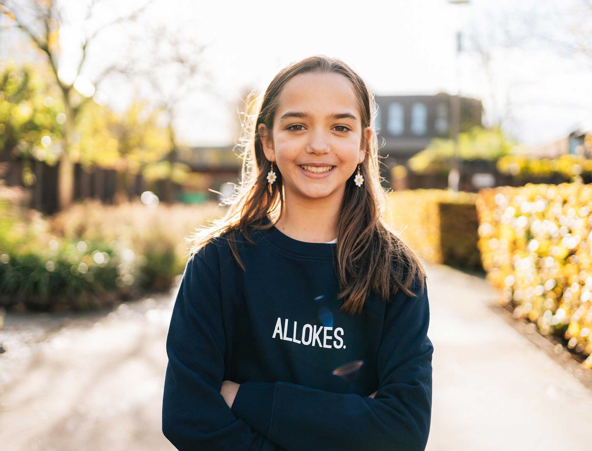Meisje met een donkerblauwe sweater met opdruk ALLOKES. voor kinderen