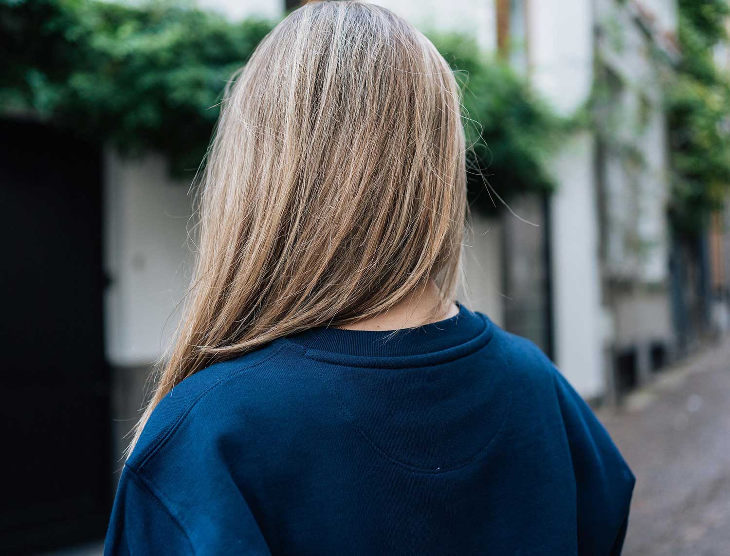 Achterkant van een donkerblauwe sweater met opdruk ALLOKES.