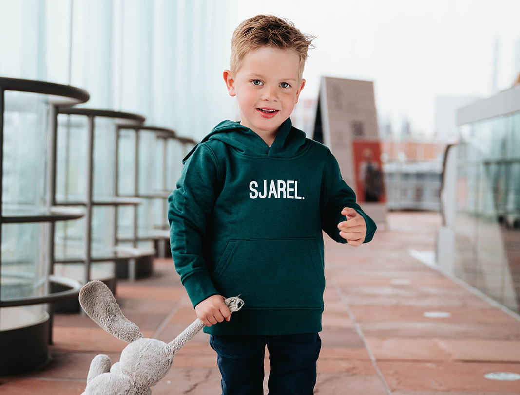 Jongen met een groene hoodie met opdruk SJAREL.