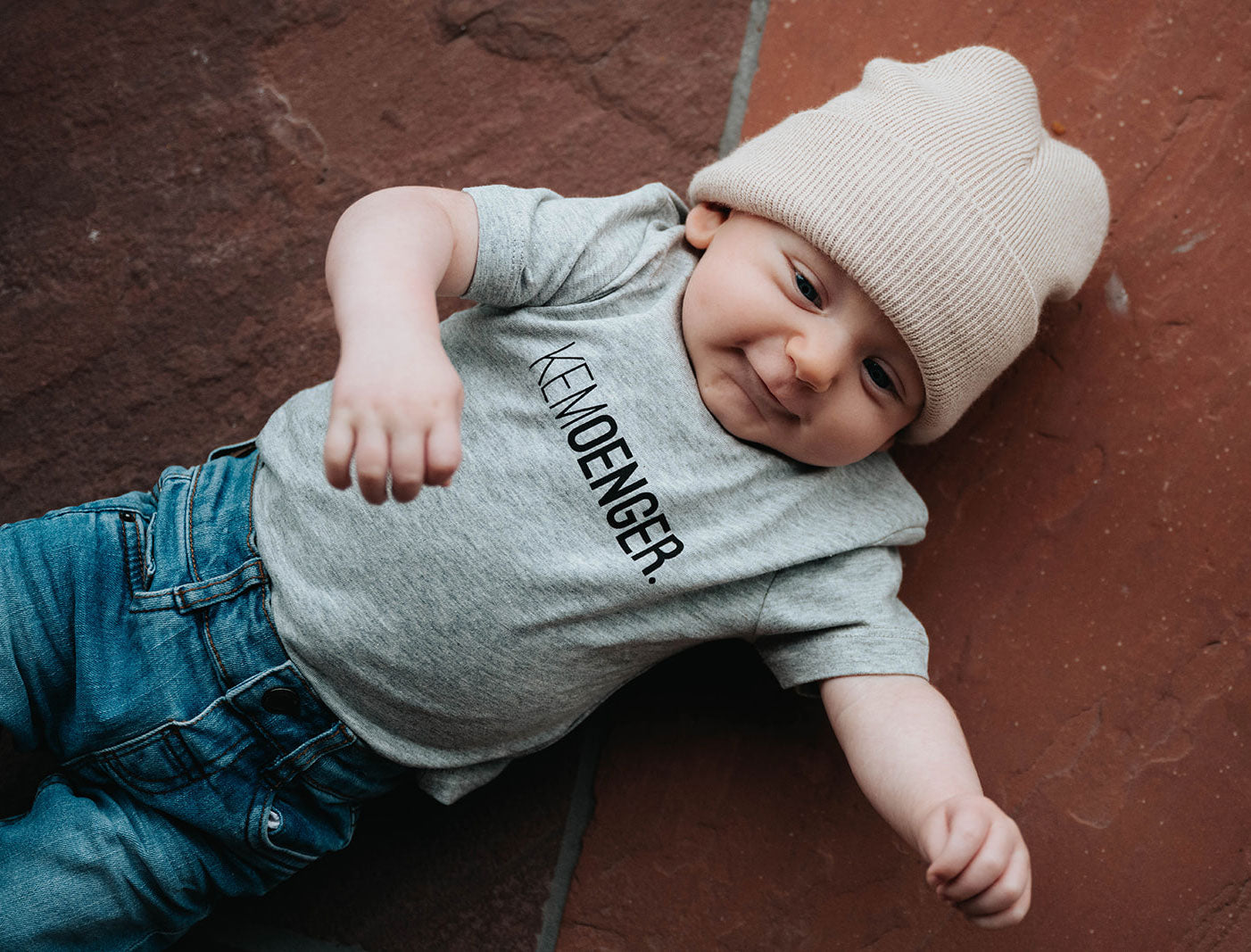 Baby met een grijze T-shirt voor baby's met opdruk KEMOENGER.