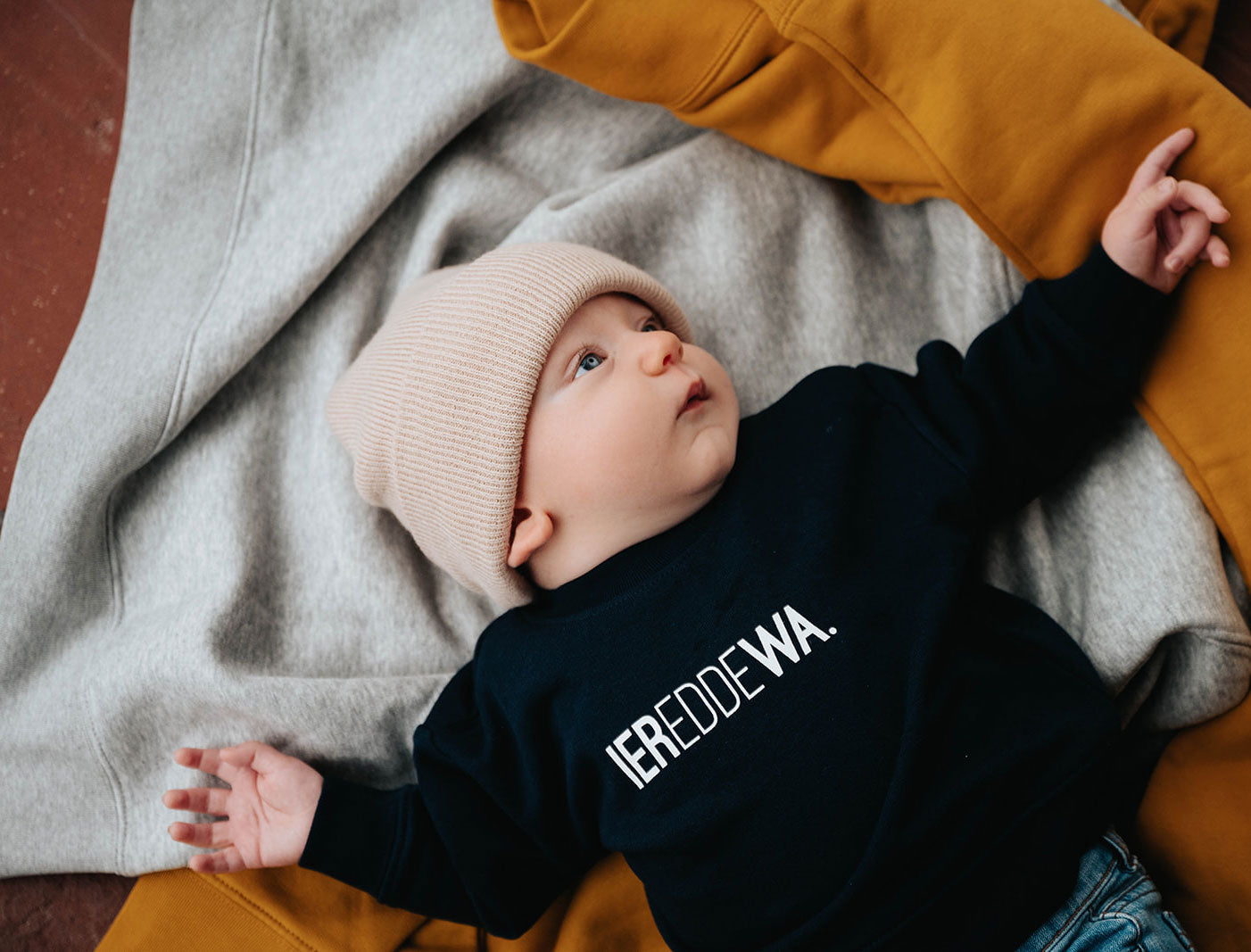 Baby met een blauwe trui voor baby's met opdruk IEREDDEWA.