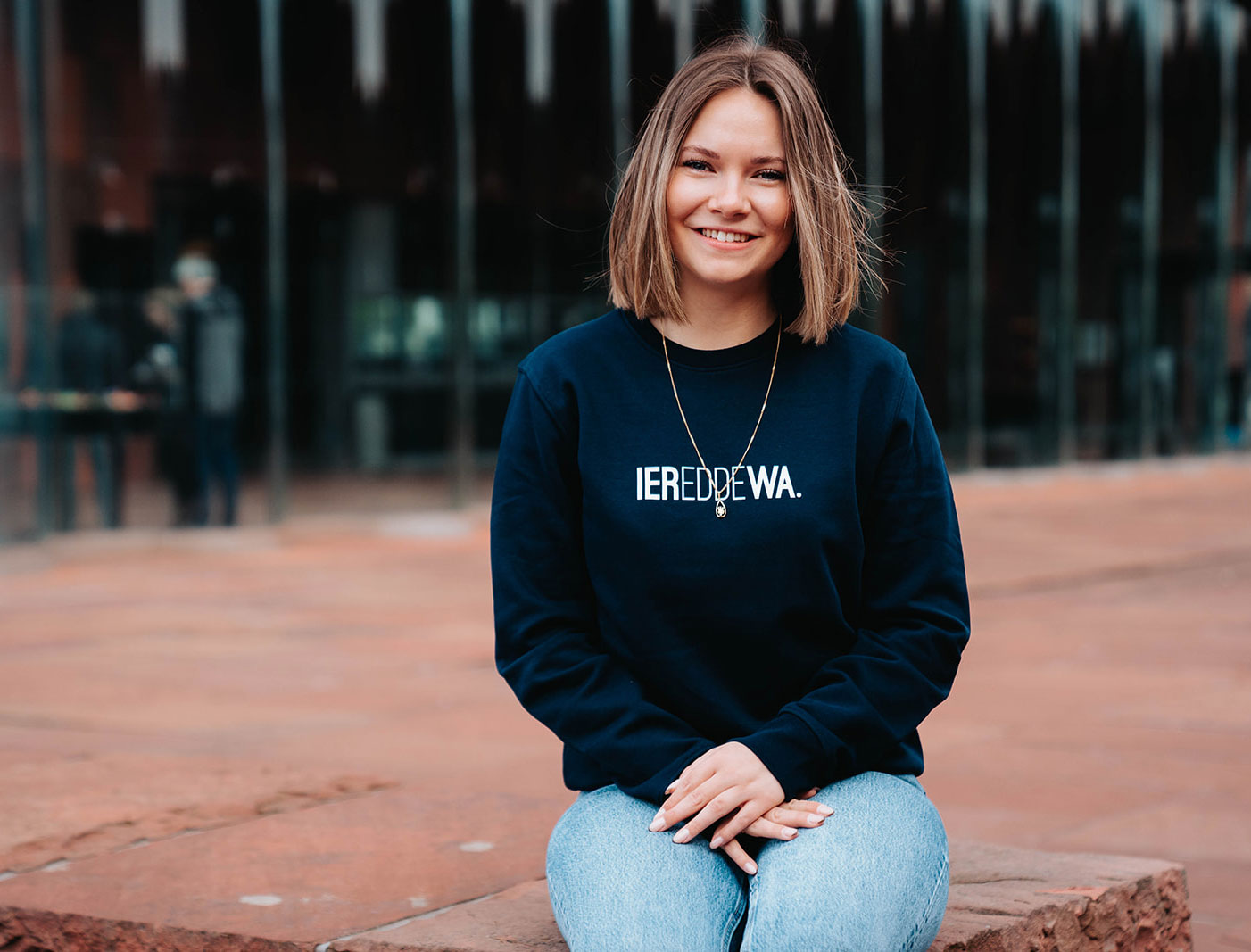 Vrouw met blauwe trui met opdruk IEREDDEWA.