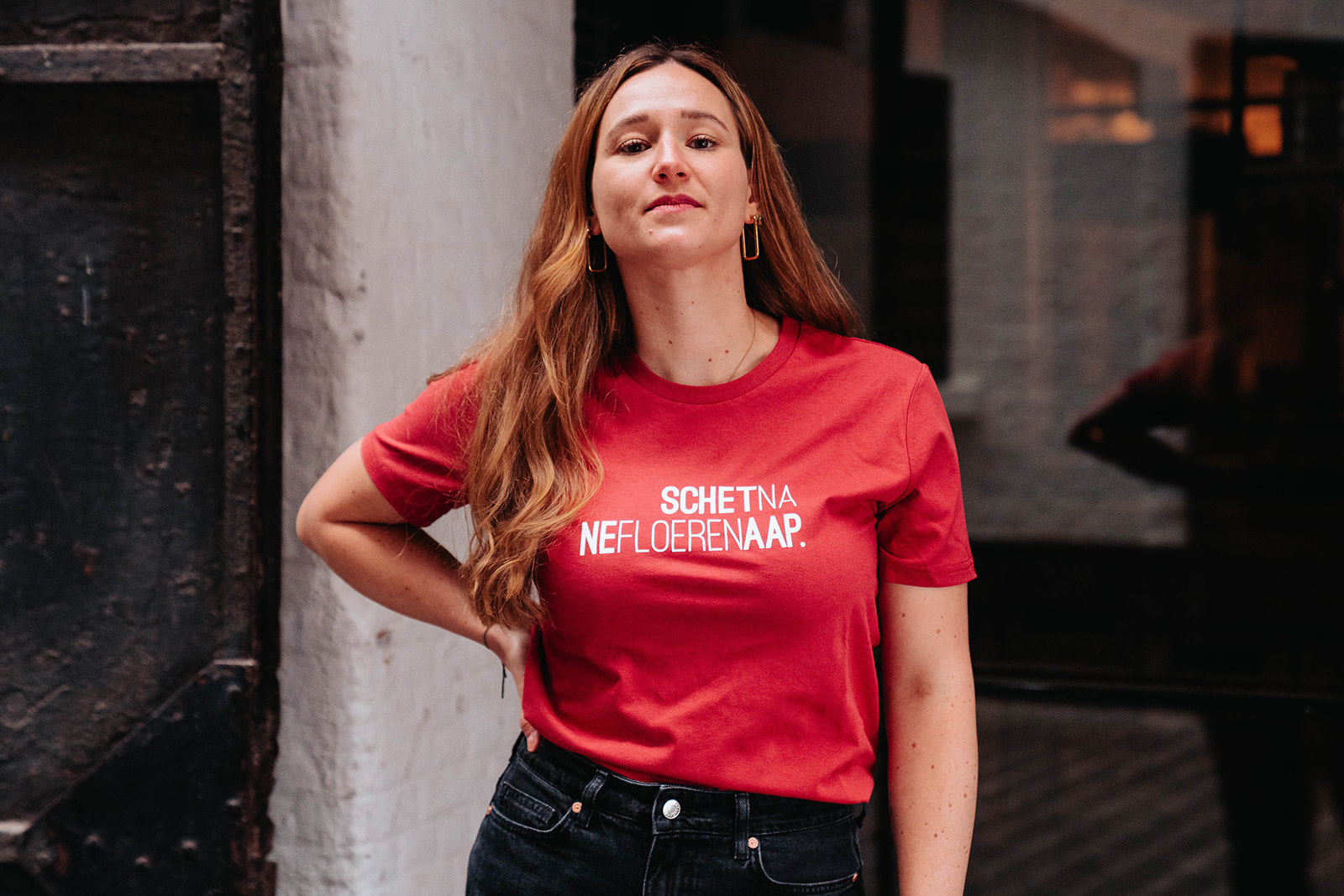 Vrouw met een rode T-shirt met opdruk SCHETNANEFLOERENAAP.