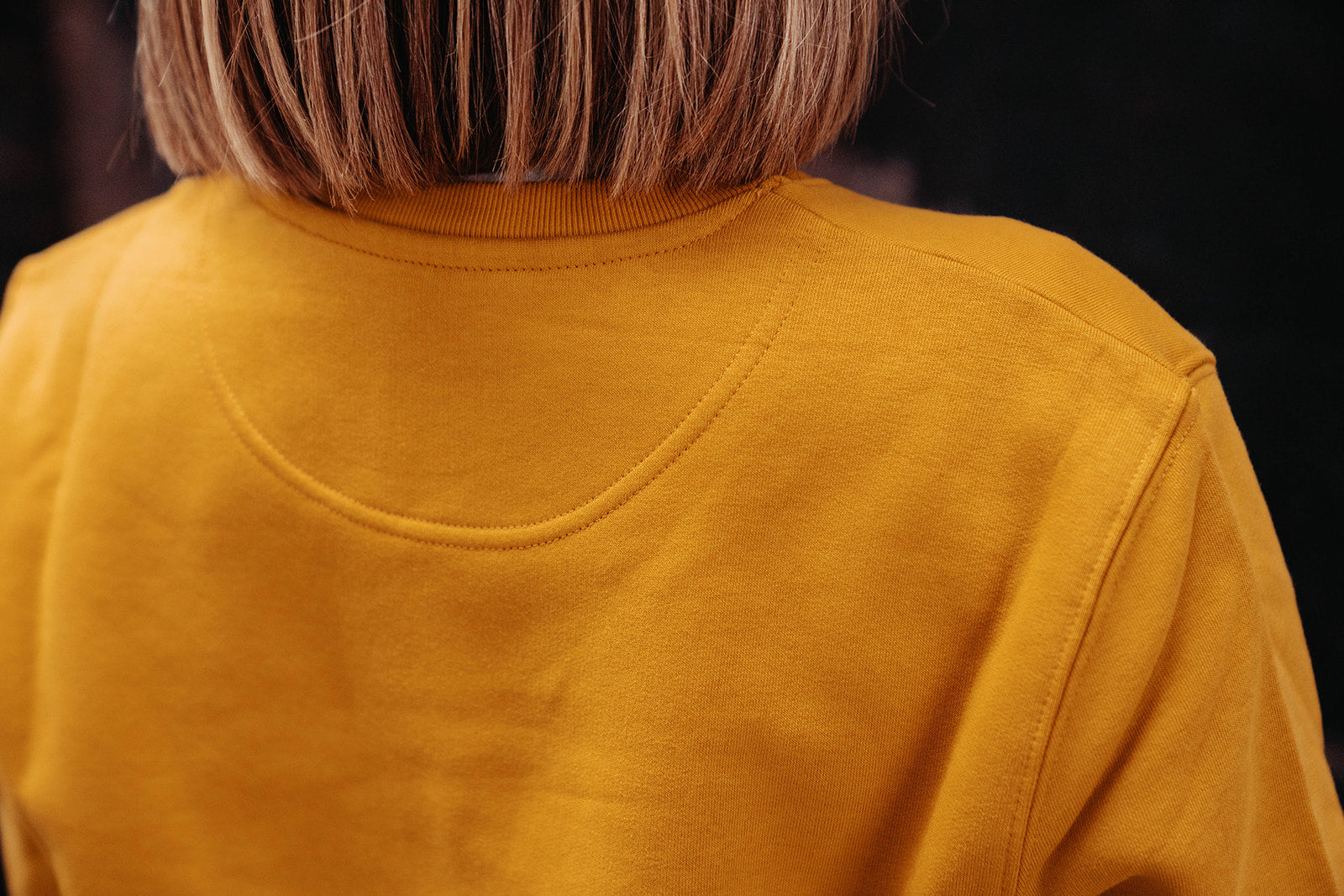 Close-up van een okerkleurige trui.
