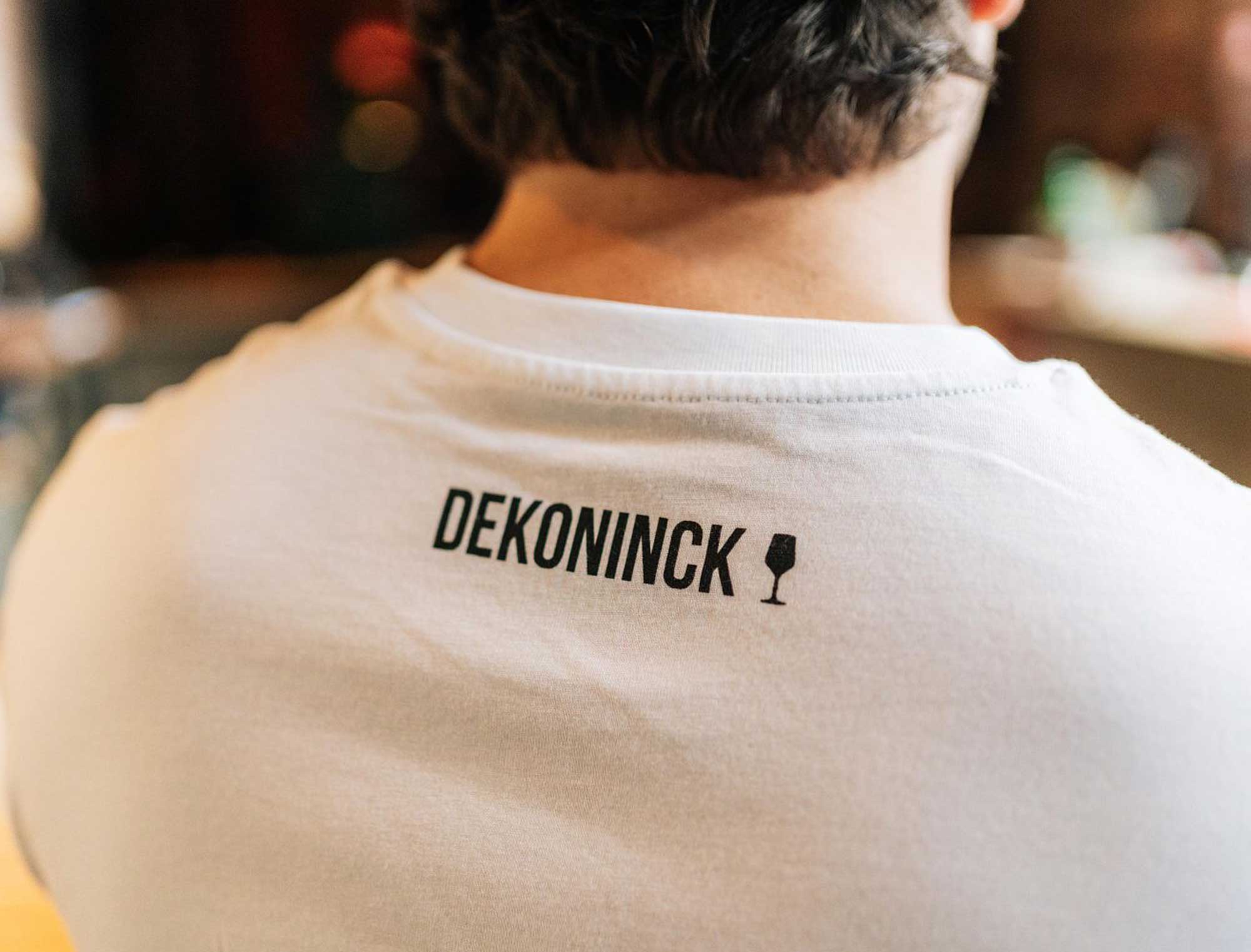 Close-up van de achterkant van een witte T-shirt met het logo van De Koninck.