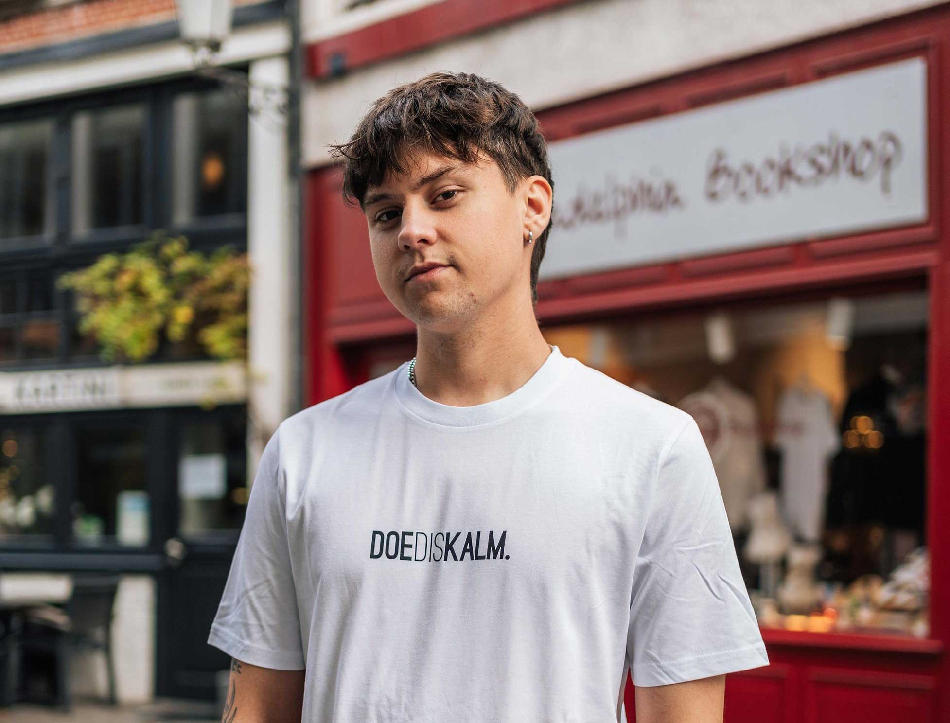 Man met een witte T-shirt met opdruk DOEDISKALM.