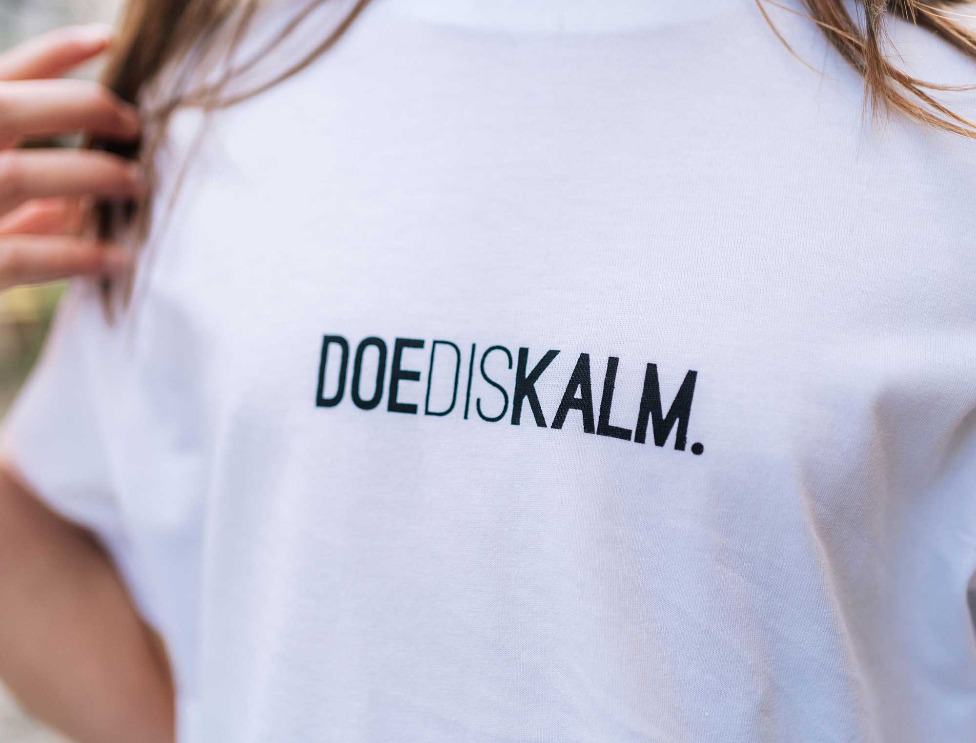 Close-up van witte T-shirt met opdruk DOEDISKALM.