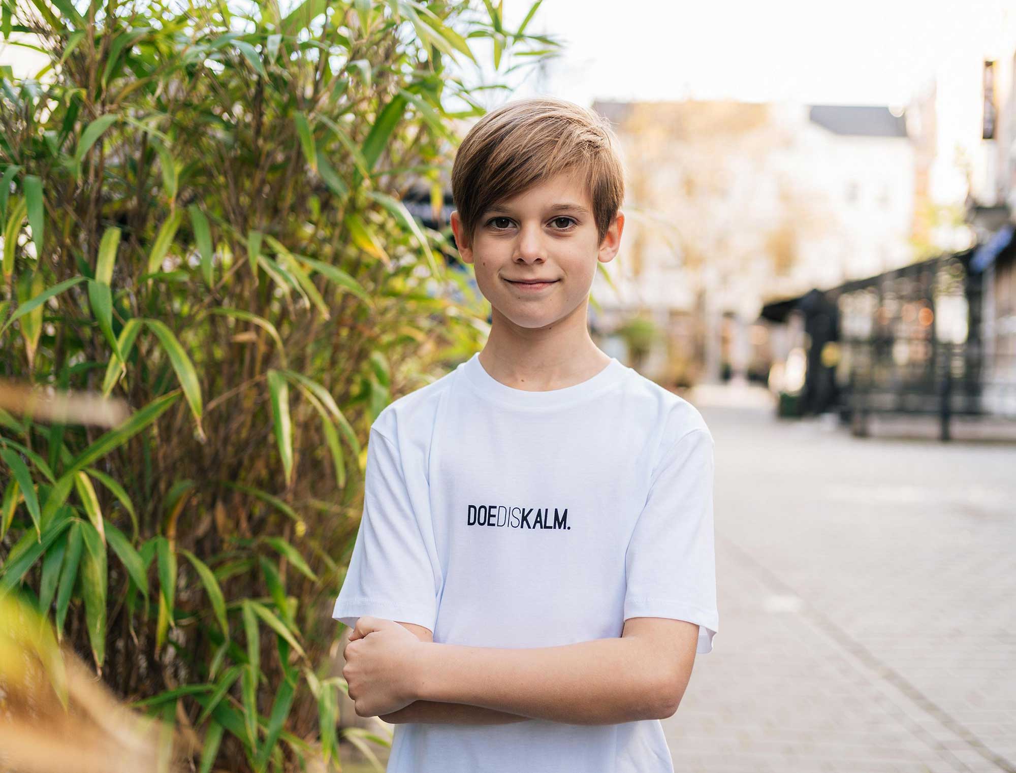 jongen met witte T-shirt met opdruk DOEDISKALM.