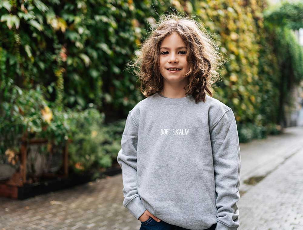 Jongen met een grijze sweater met opdruk DOEDISKALM. voor kinderen