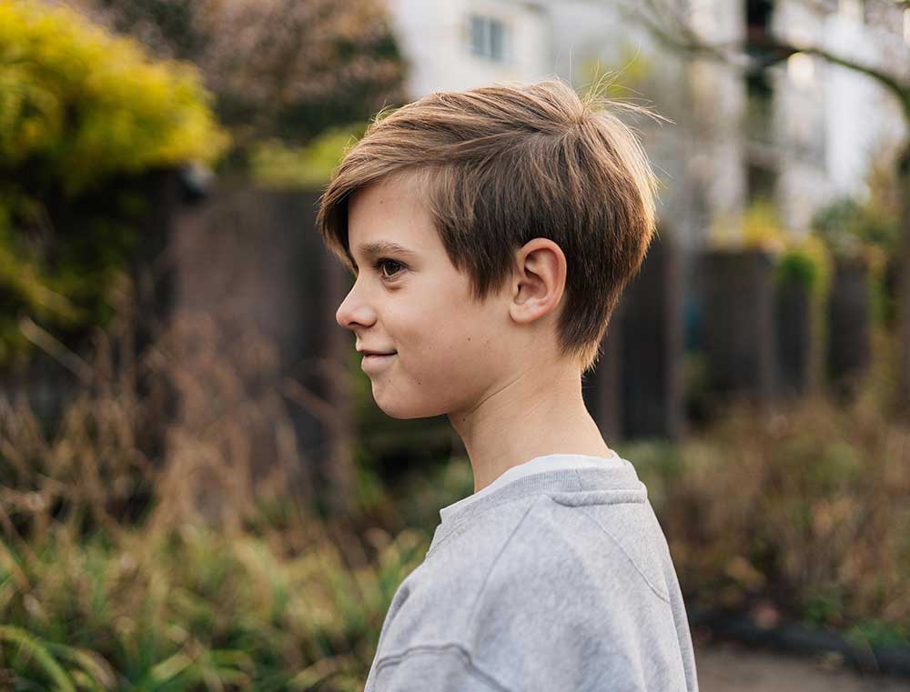 Jongen met een grijze sweater met opdruk DOEDISKALM. voor kinderen