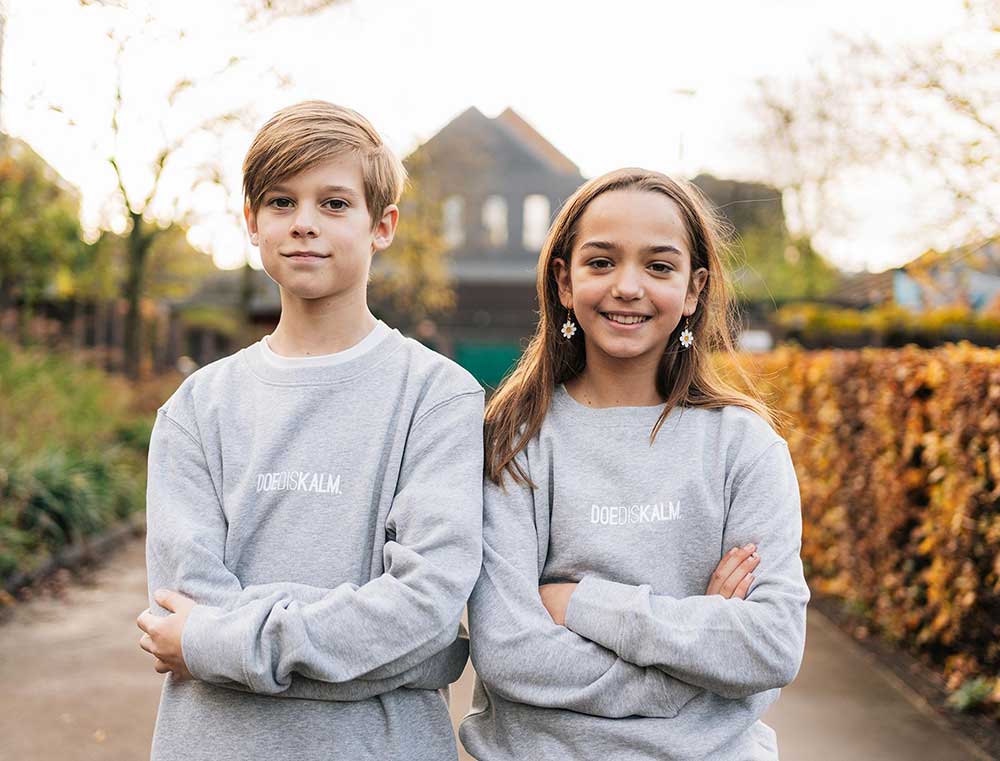 Jongen en meisje met een grijze sweater met opdruk DOEDISKALM. voor kinderen