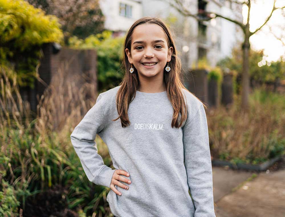 Meisje met een grijze sweater met opdruk DOEDISKALM. voor kinderen