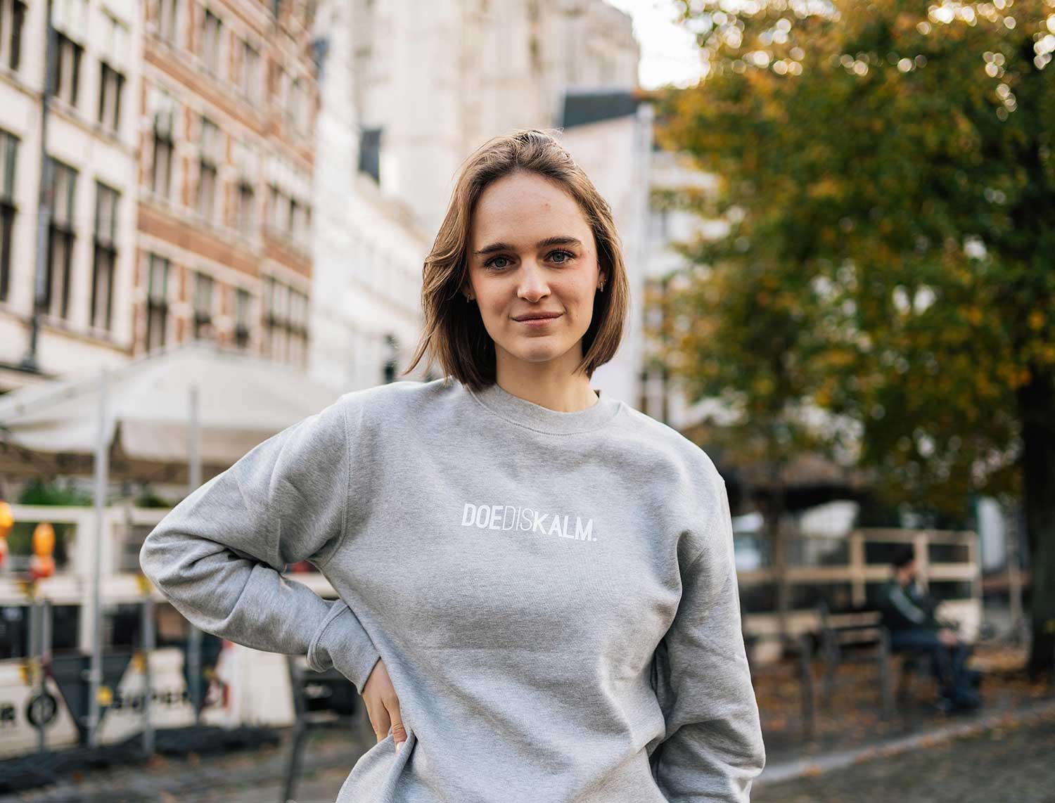 Vrouw met een grijze sweater met opdruk DOEDISKALM.