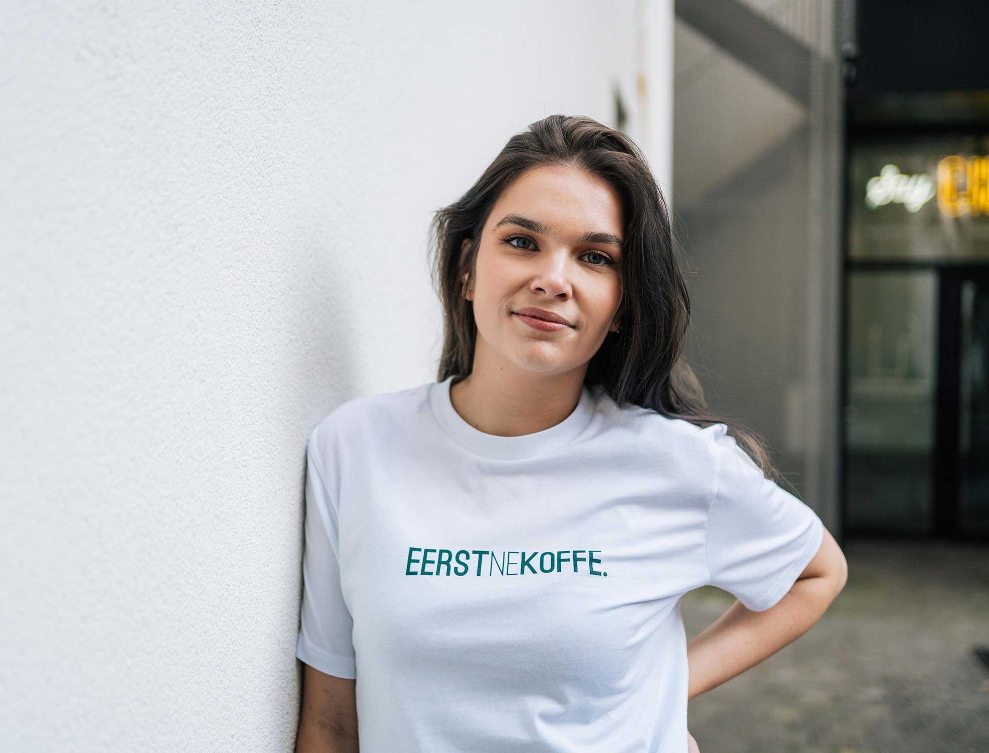 Vrouw met een witte T-shirt met opdruk EERSTNEKOFFE. in 't groen.