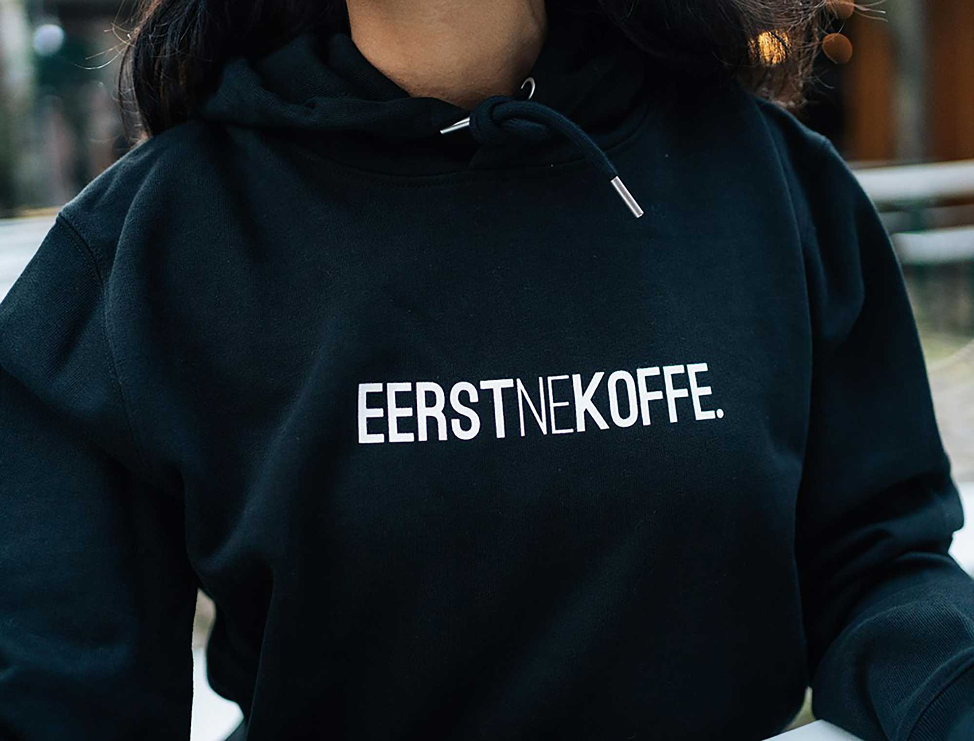 Close-up van blauwe hoodie met opdruk EERSTNEKOFFE.