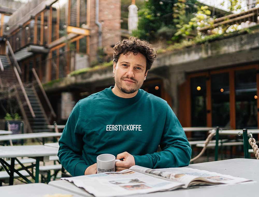 Man met een groene sweater met opdruk EERSTNEKOFFE.