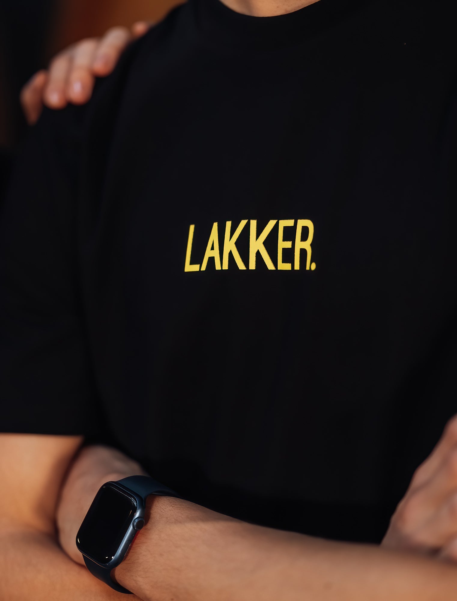 Close-up van zwarte T-shirt met gele opdruk LAKKER.