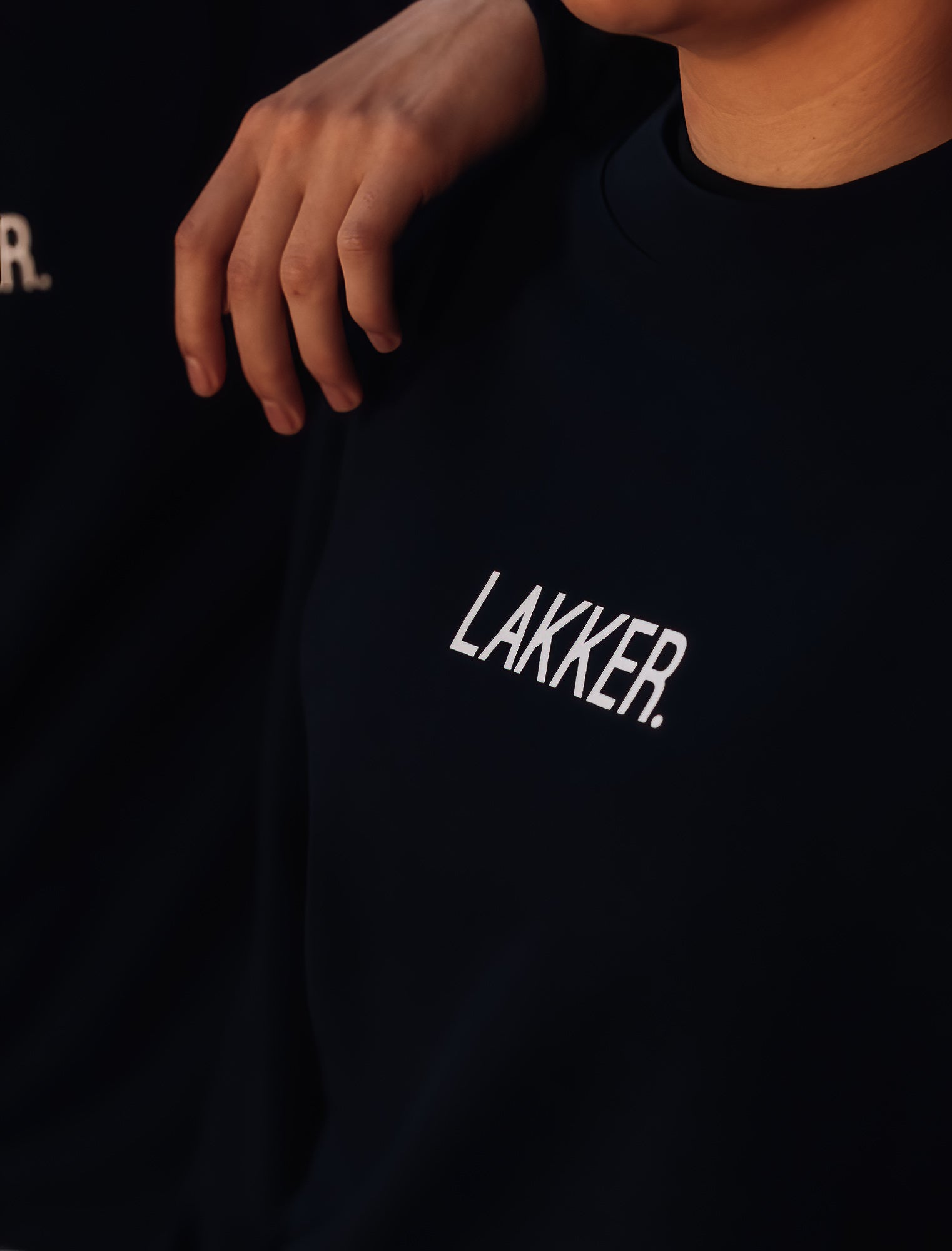 Close-up van zwarte unisex sweater met opdruk LAKKER. 