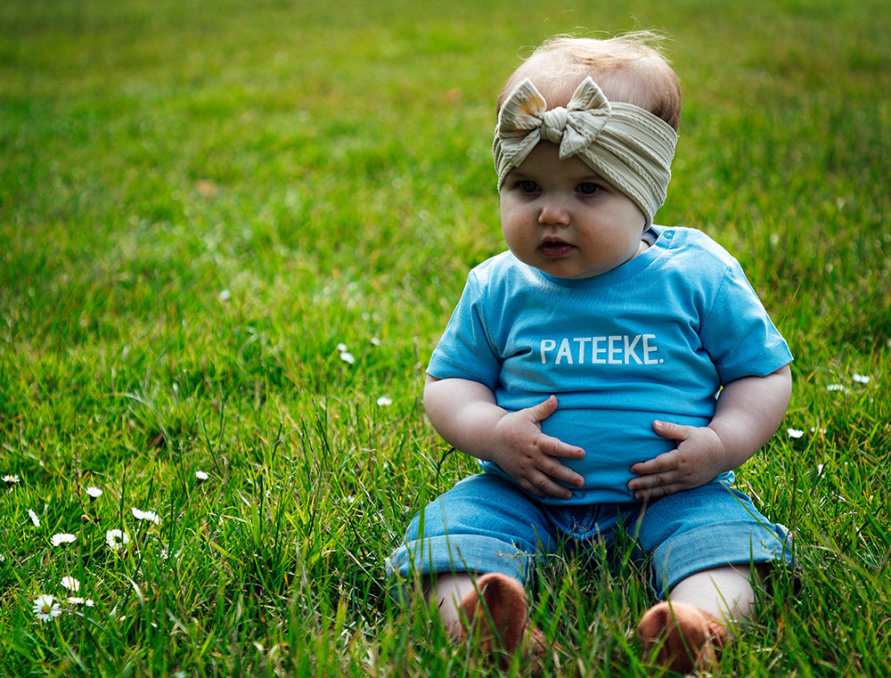 Baby met blauwe T-shirt met opdruk PATEEKE.