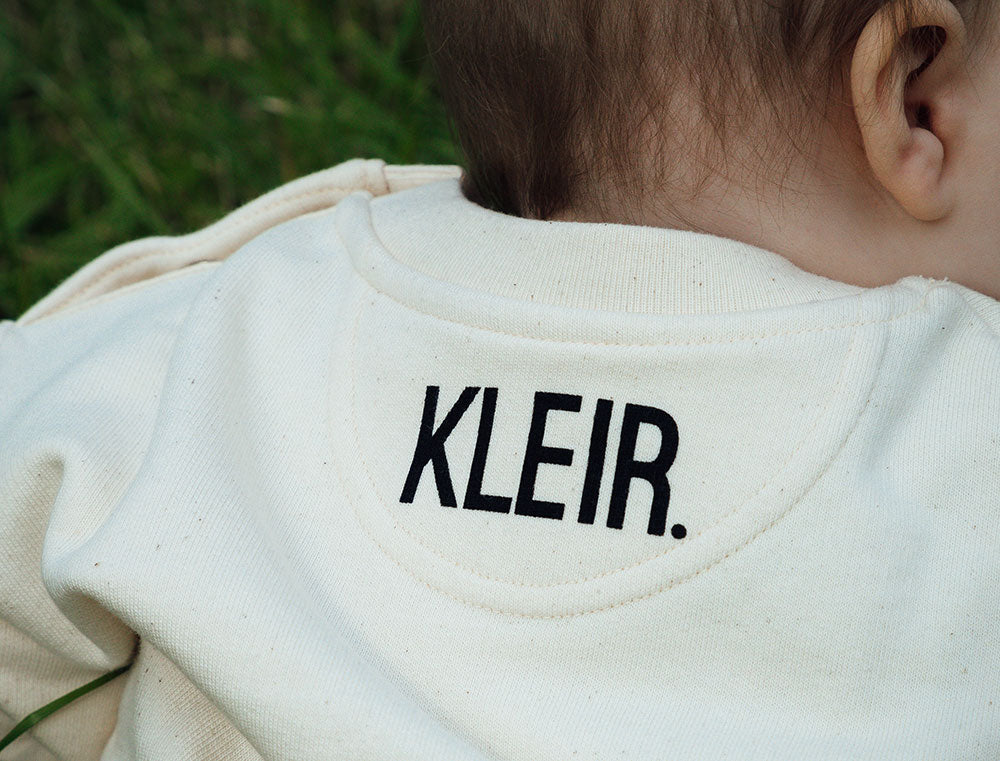 Witte sweater voor baby's met opdruk KLEIR. op de achterkant