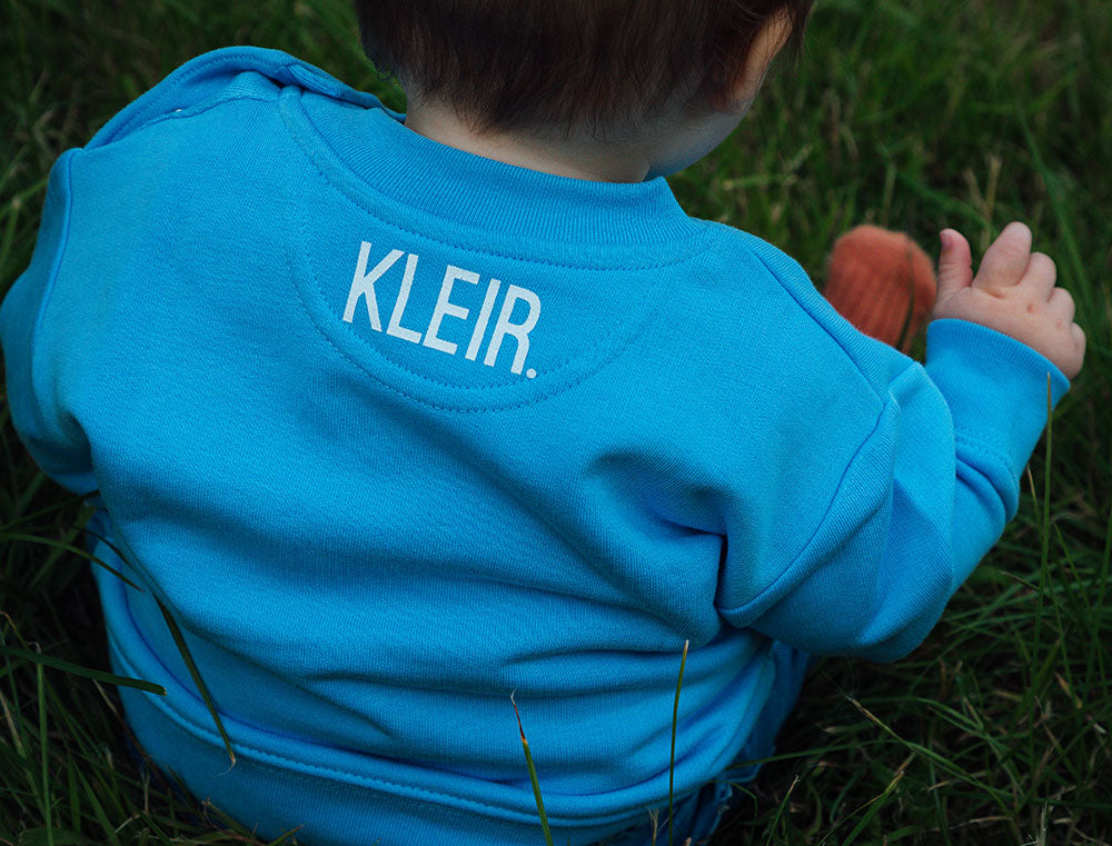 Blauwe sweater voor baby's met opdruk KLEIR. op de achterkant