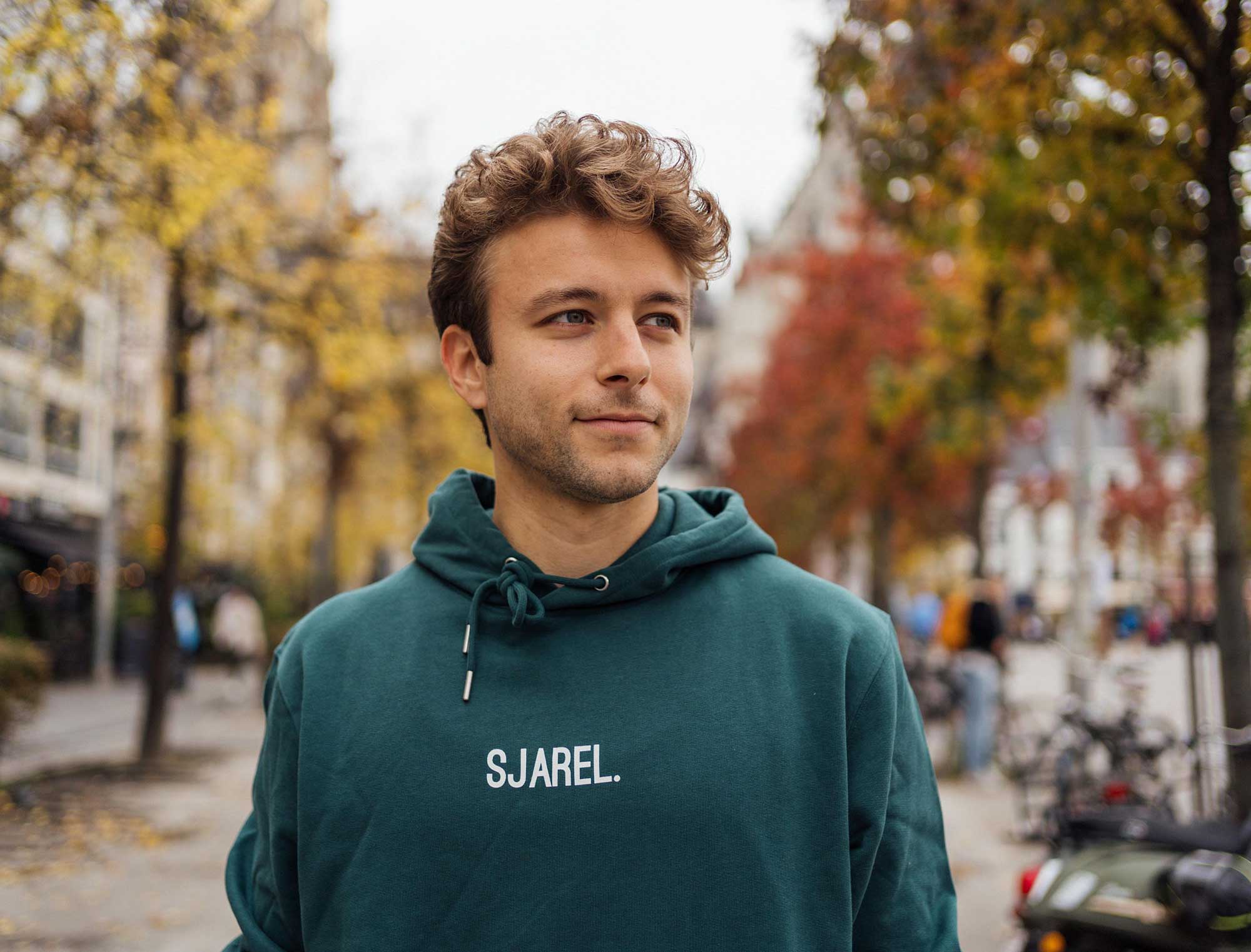 Man met een groene hoodie met opdruk SJAREL.