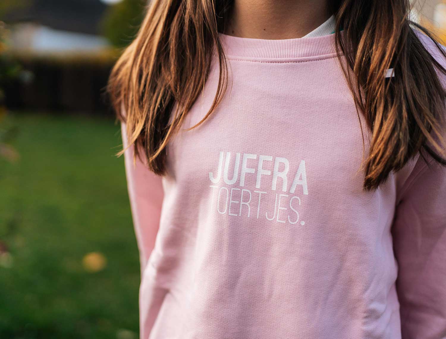 Close-up van een roze sweater met opdruk JUFFRA TOERTJES. voor kinderen