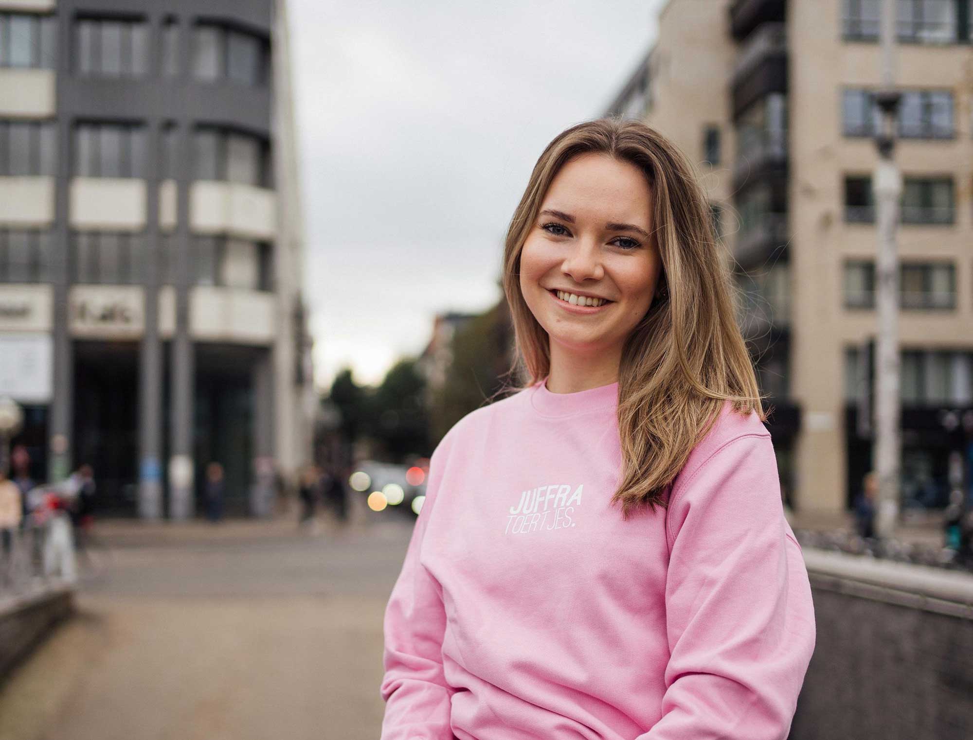 Vrouw met een roze sweater met opdruk JUFFRA TOERTJES.