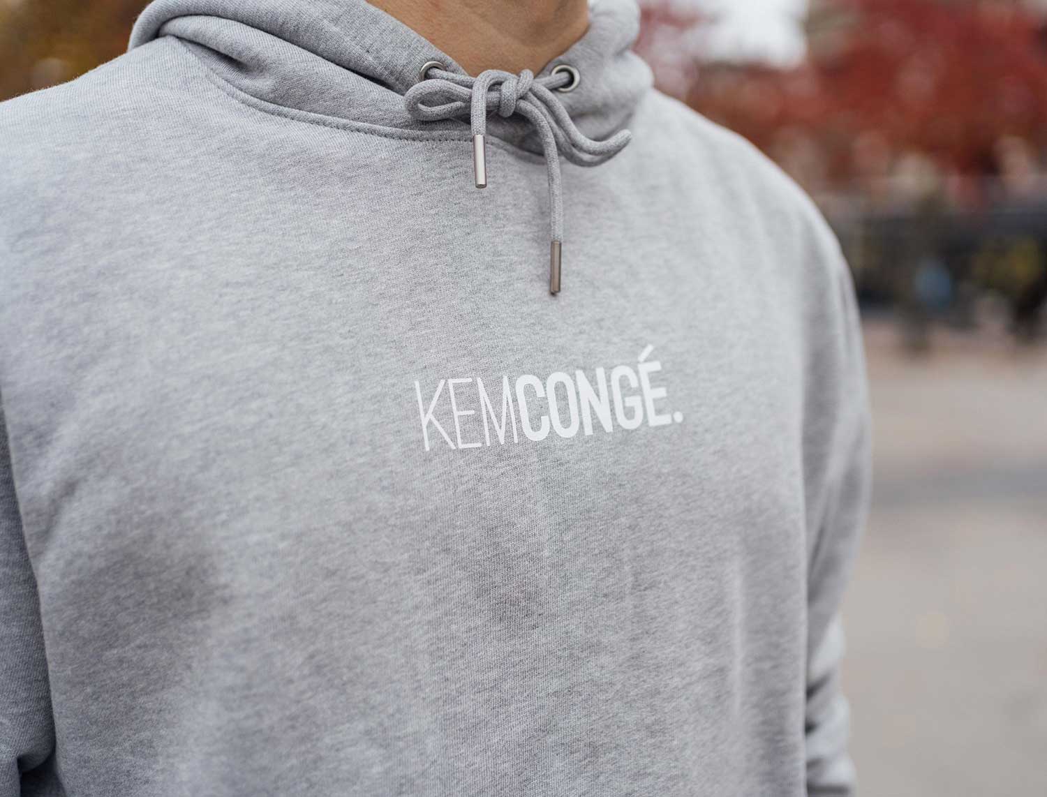 Close-up van een grijze hoodie met opdruk KEMCONGE.
