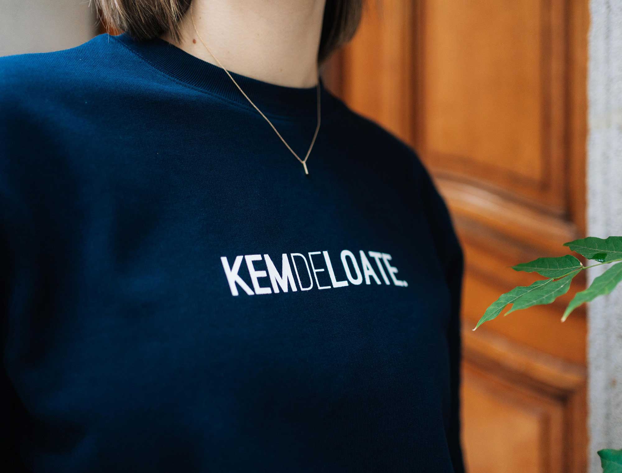 Close-up van een donkerblauwe sweater met opdruk KEMDELOATE.